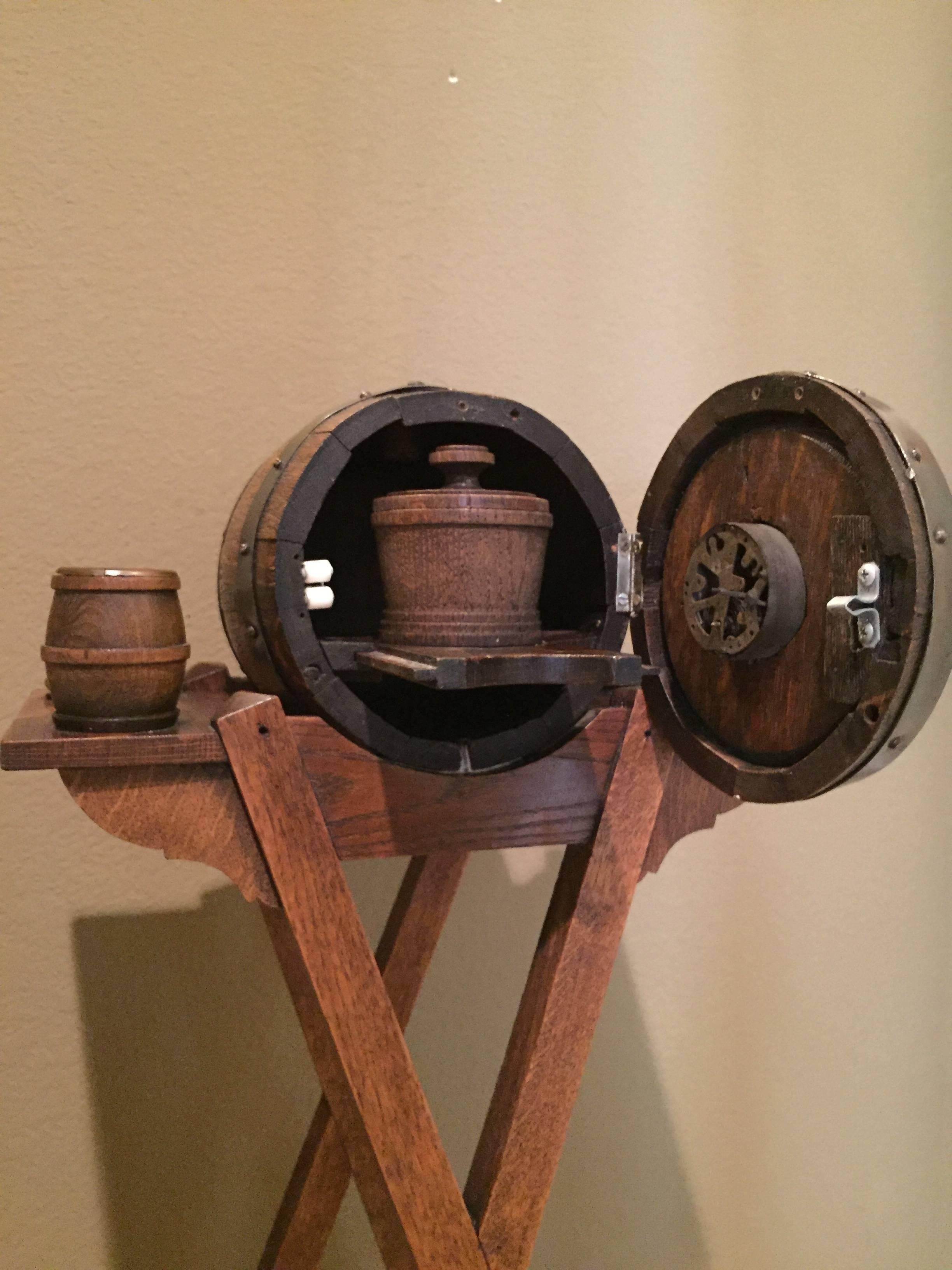 This fantastic cigar stand is extremely rare and complete with cigar cutter, ashtrays, match holder, cigarette holder and the front of the barrel opens to
reveal a pull-out tray that hold a tobacco humidor, the clock is present though not working.