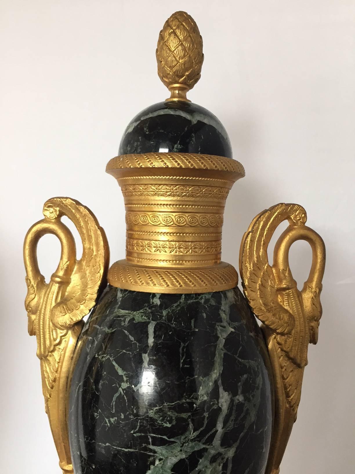 A fabulous pair of mantel urns in marble and beautifully cast gilt bronze in the form of swans, the green to black color of the marble with quartz veins, the foot
with decorative mounts in the form of griffins, bows and wreaths. A fantastic pair in
