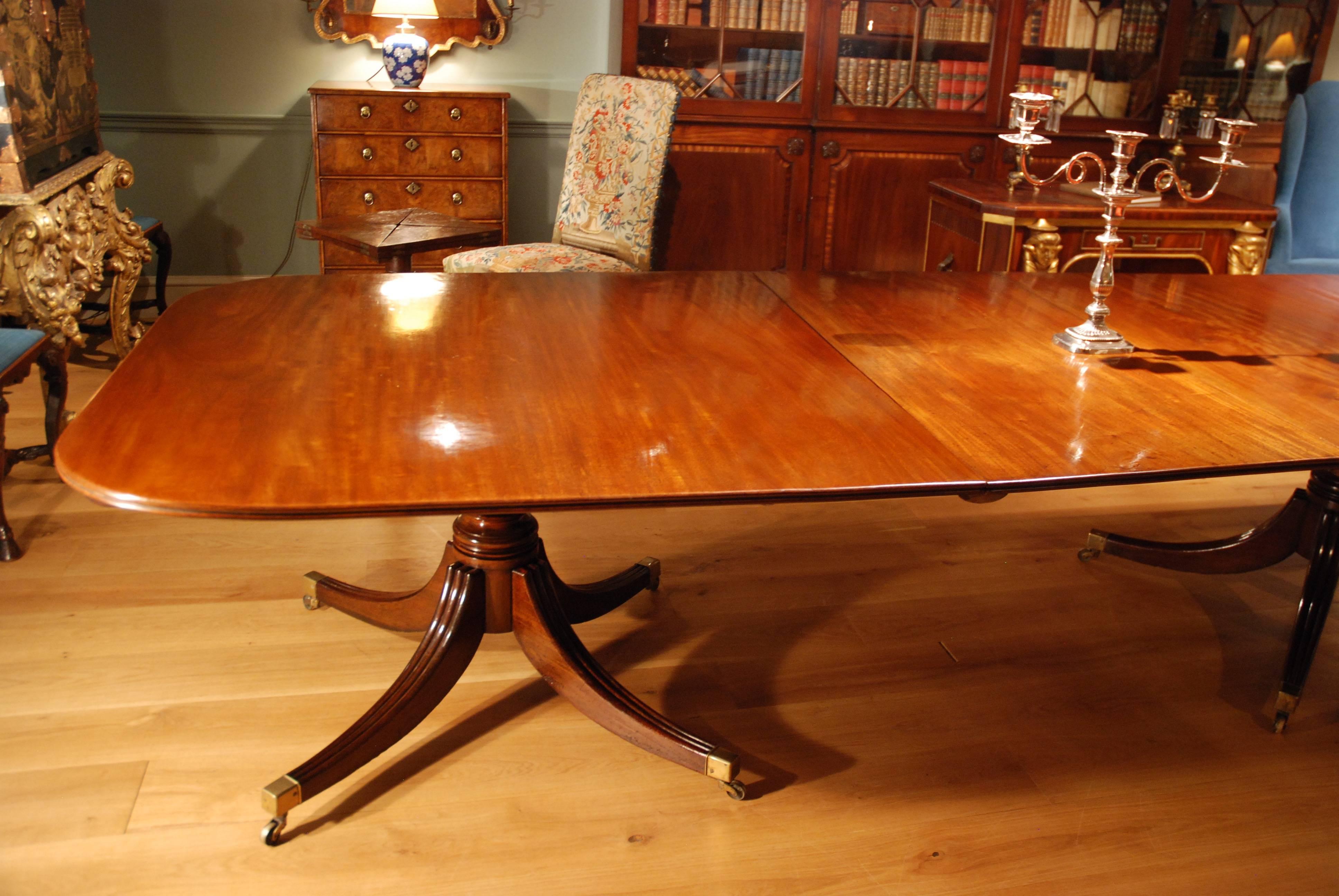 A large George III mahogany dining table of excellent warm colour, standing on three turned pillars each supported by four splay legs terminating in brass cap castors. This table consists of three sections all of which can be tipped to a vertical