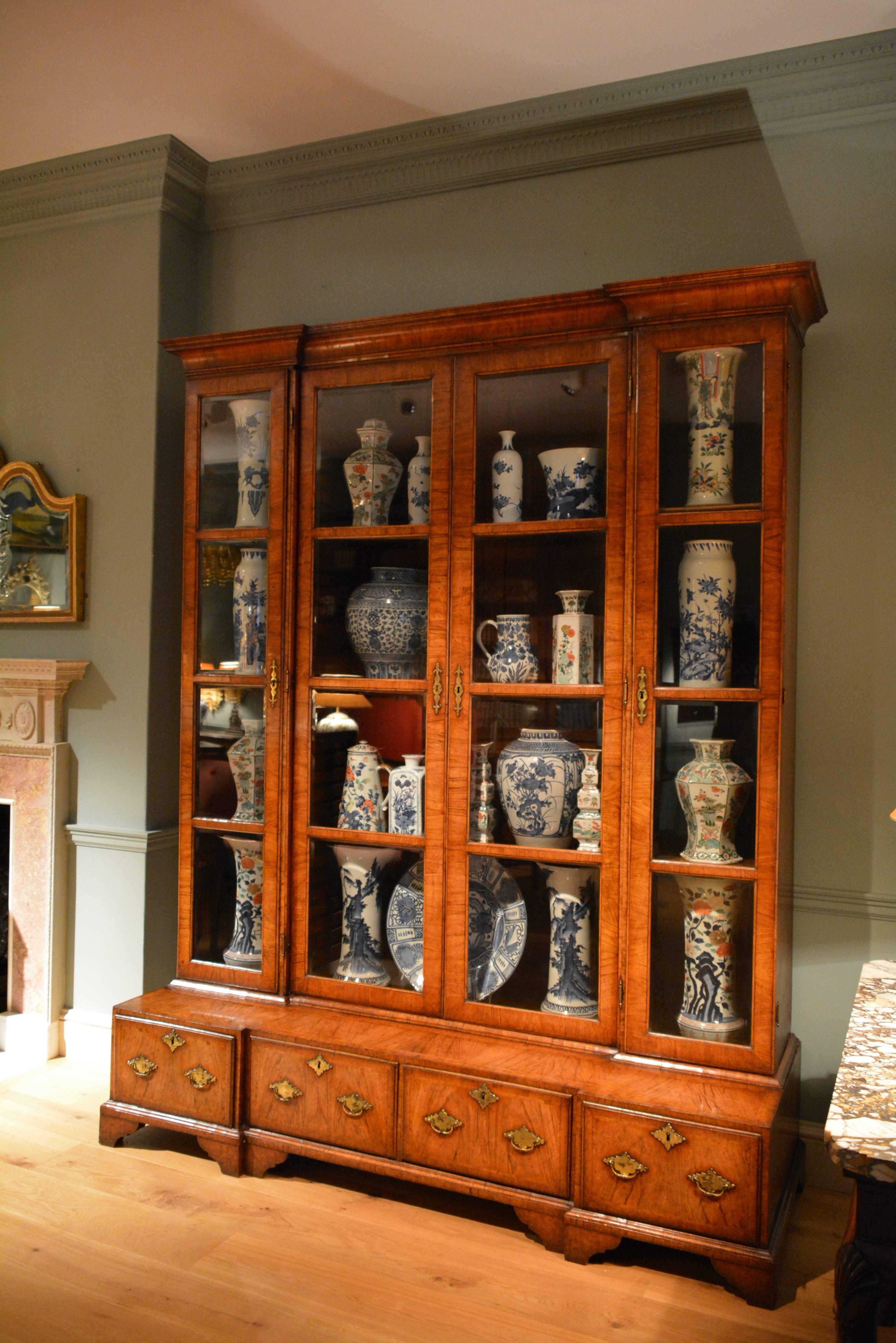A rare large George II inverted breakfront veneered walnut China cabinet. The square glazed doors retaining their original hand bevelled glass, standing on a projecting inverted breakfront base, containing four drawers, the whole retaining it's