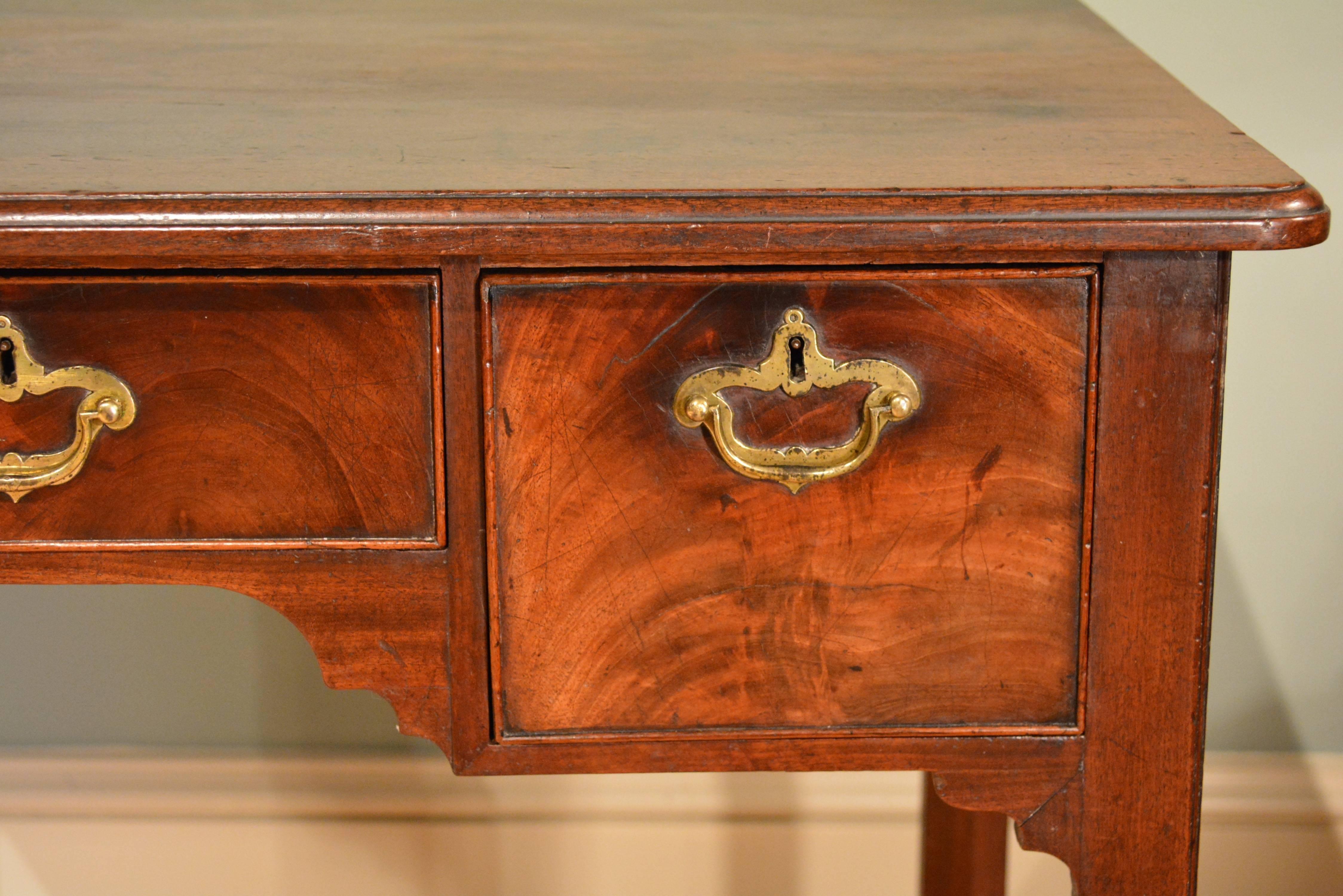 A George III mahogany centre table, the moulded top with rounded corners above three finely figured drawers to one side, retaining their original handles, the whole standing on square legs with shaped brackets.