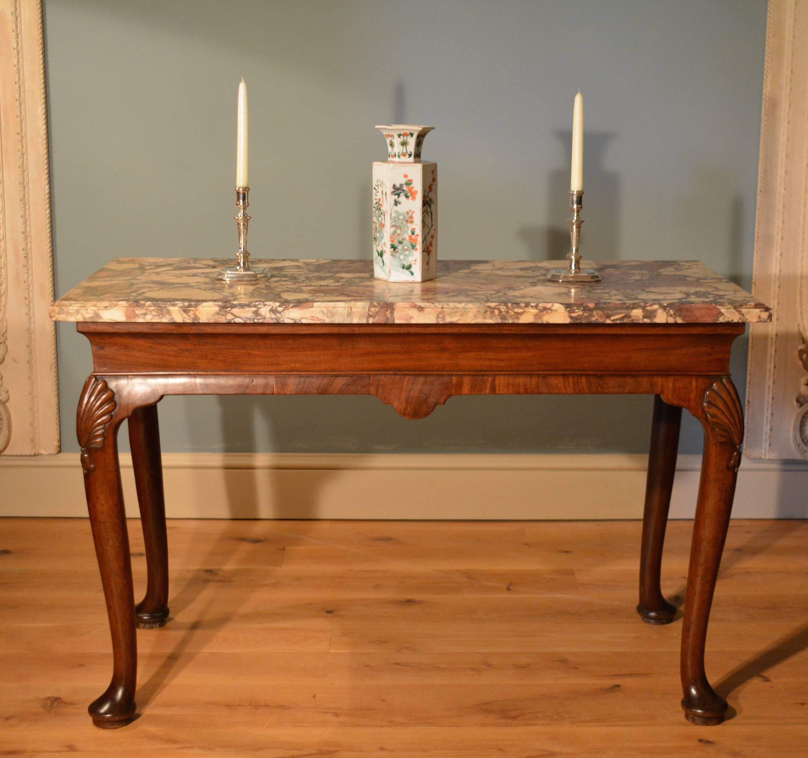 A George II mahogany marble-top side table, the cavetto frieze supporting the 18th century marble top below which are four cabriole legs carved with shells to the knees ending in plain pad fee.