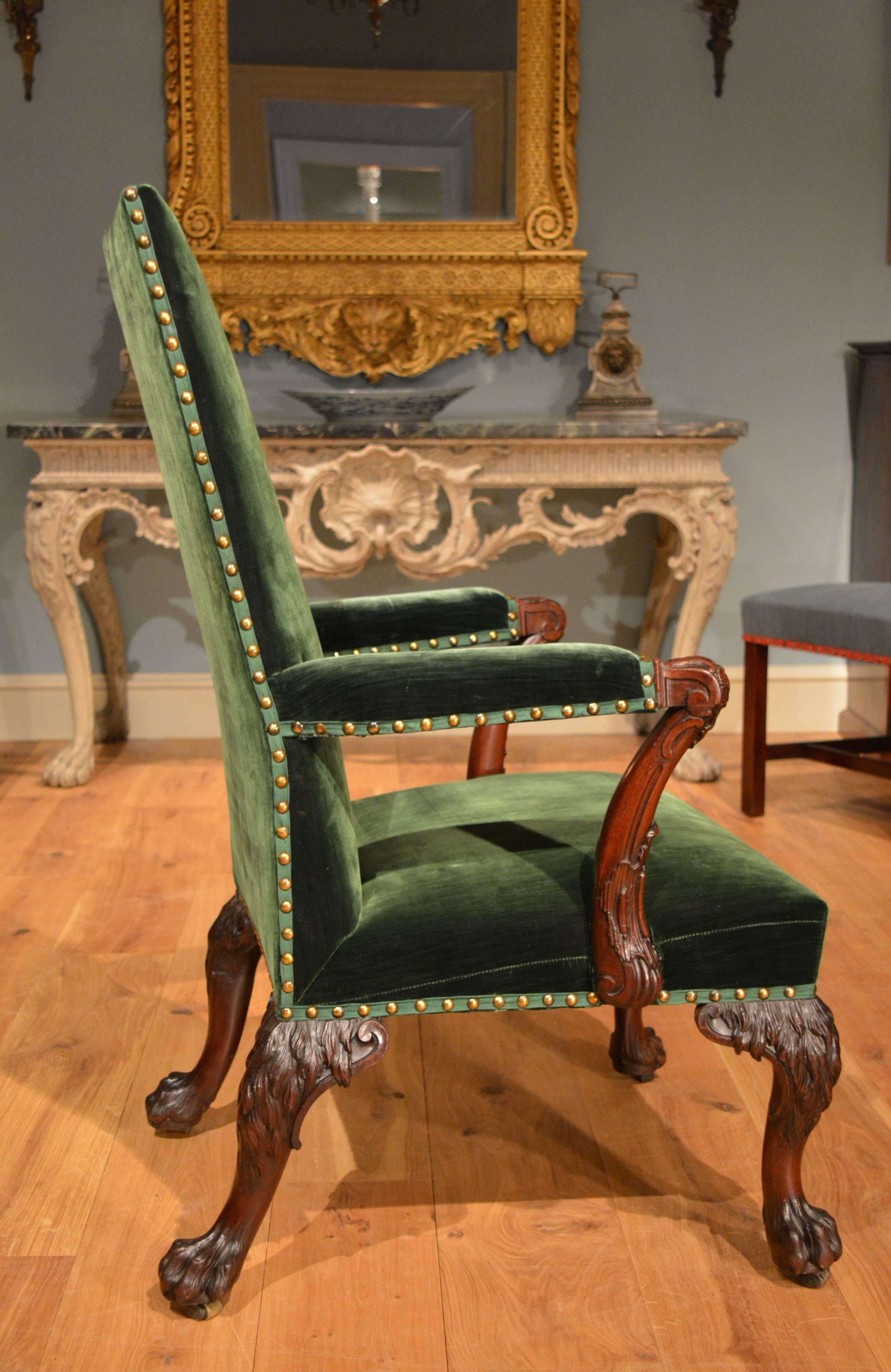 A George II finely carved mahogany armchair, the arms ending in cabochons, below which is stylised leafage incorporating 'C' scrolls, with 'C' scrolls to the legs, which are carved with hairy knees and end in paw feet. The back legs are particularly