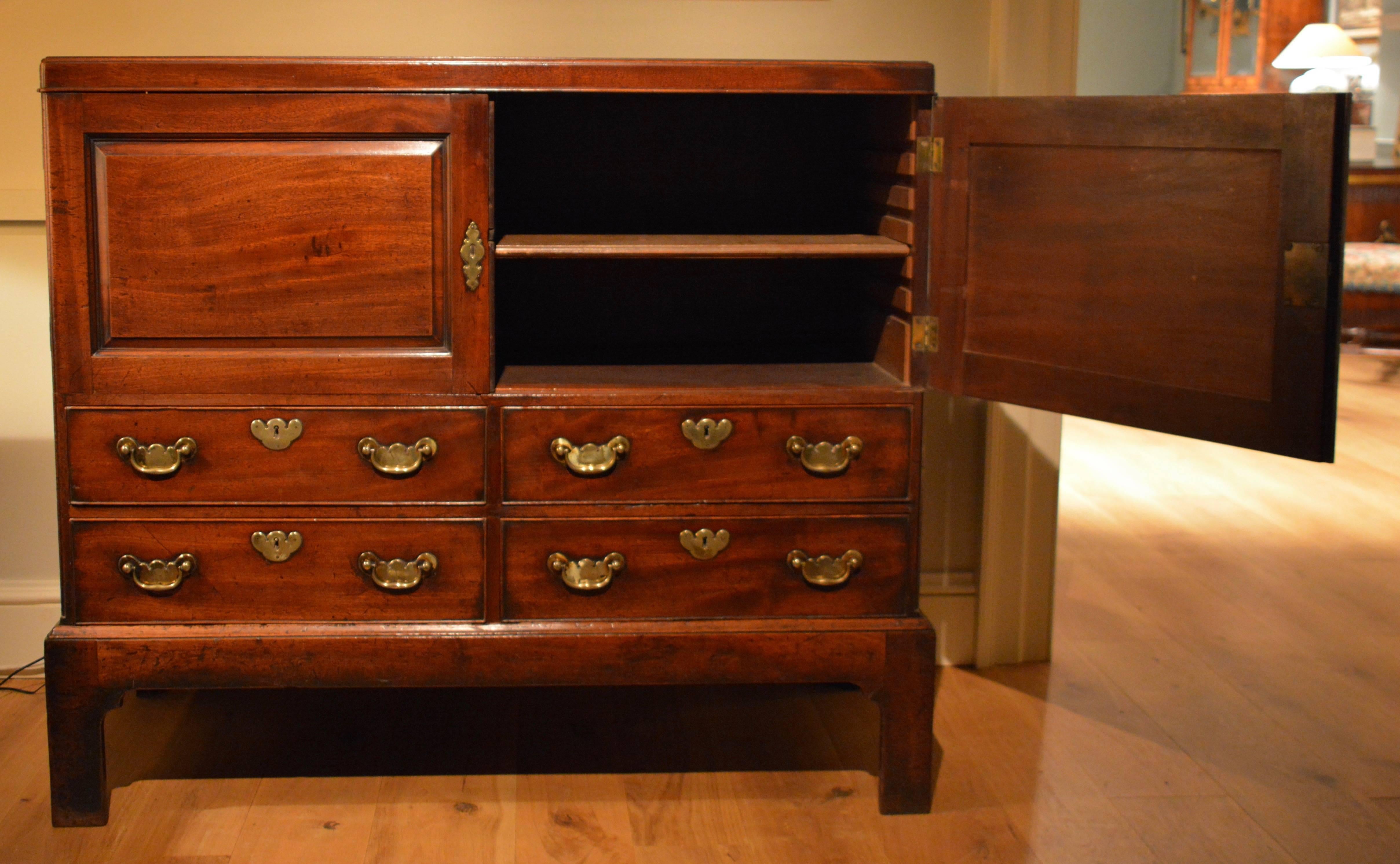 An unusual George II chest on stand incorporating a pair of cupboard doors which enclose a single adjustable shelf below which are four drawers. The whole standing on a bracket foot stand.
 