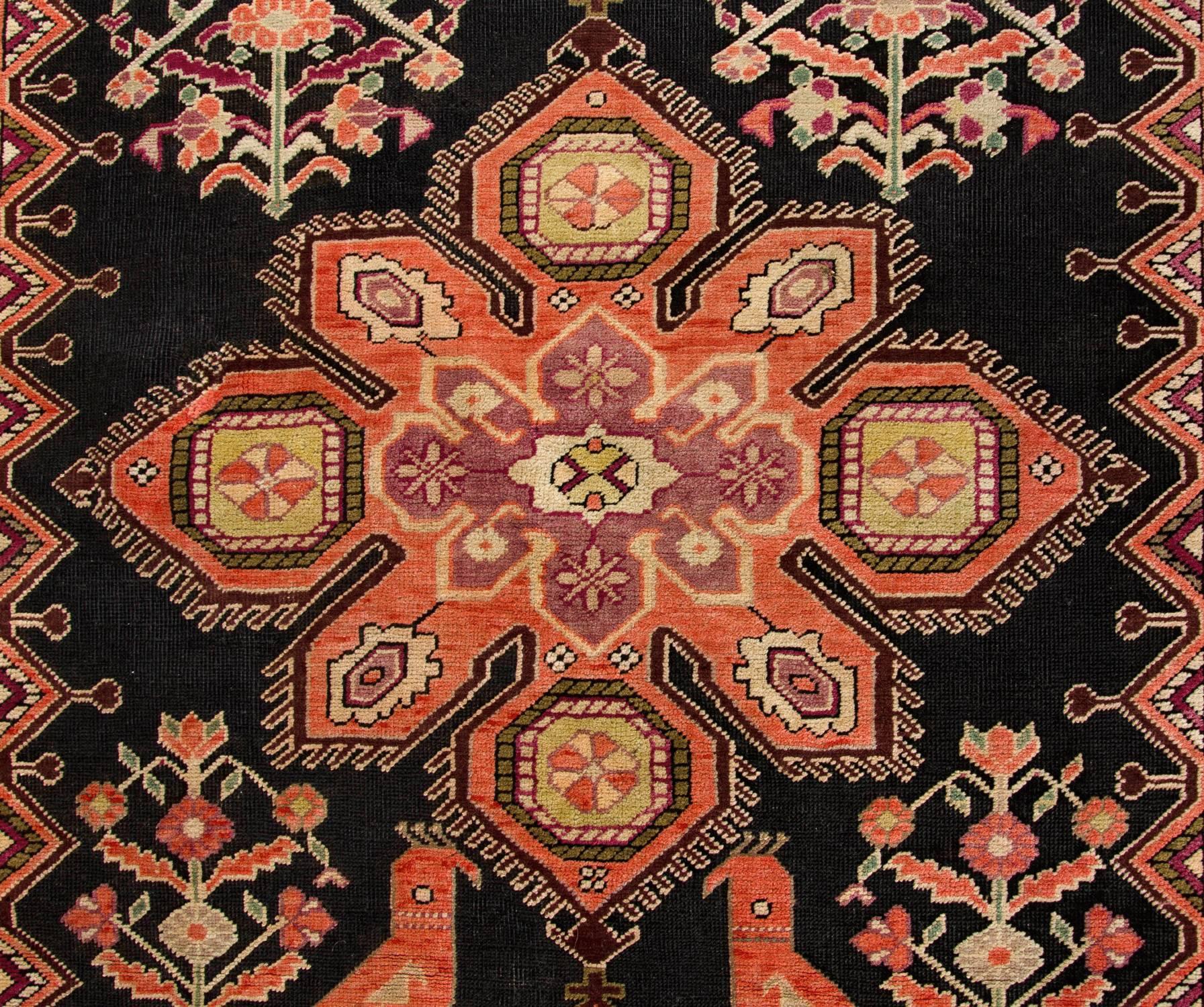 This Antique Gharabagh carpet runner has a multi-medallion design with earthy hues of brown, gold and rust red and a rich palette of colors. Featuring geometric rug design similar to those of Caucasian provenance combined with floral rug motifs