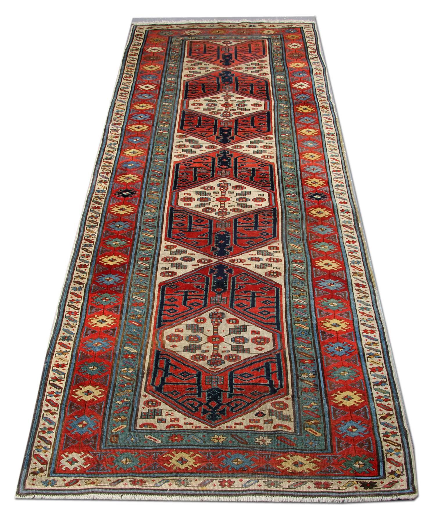 An antique rug rare Caucasian Kazak handmade carpet from the 18th century. This carpet is with an unusual geometric rug pattern on red brick background. This woven rug is surrounded by multiple contrasting floral and geometric designs. Made of the