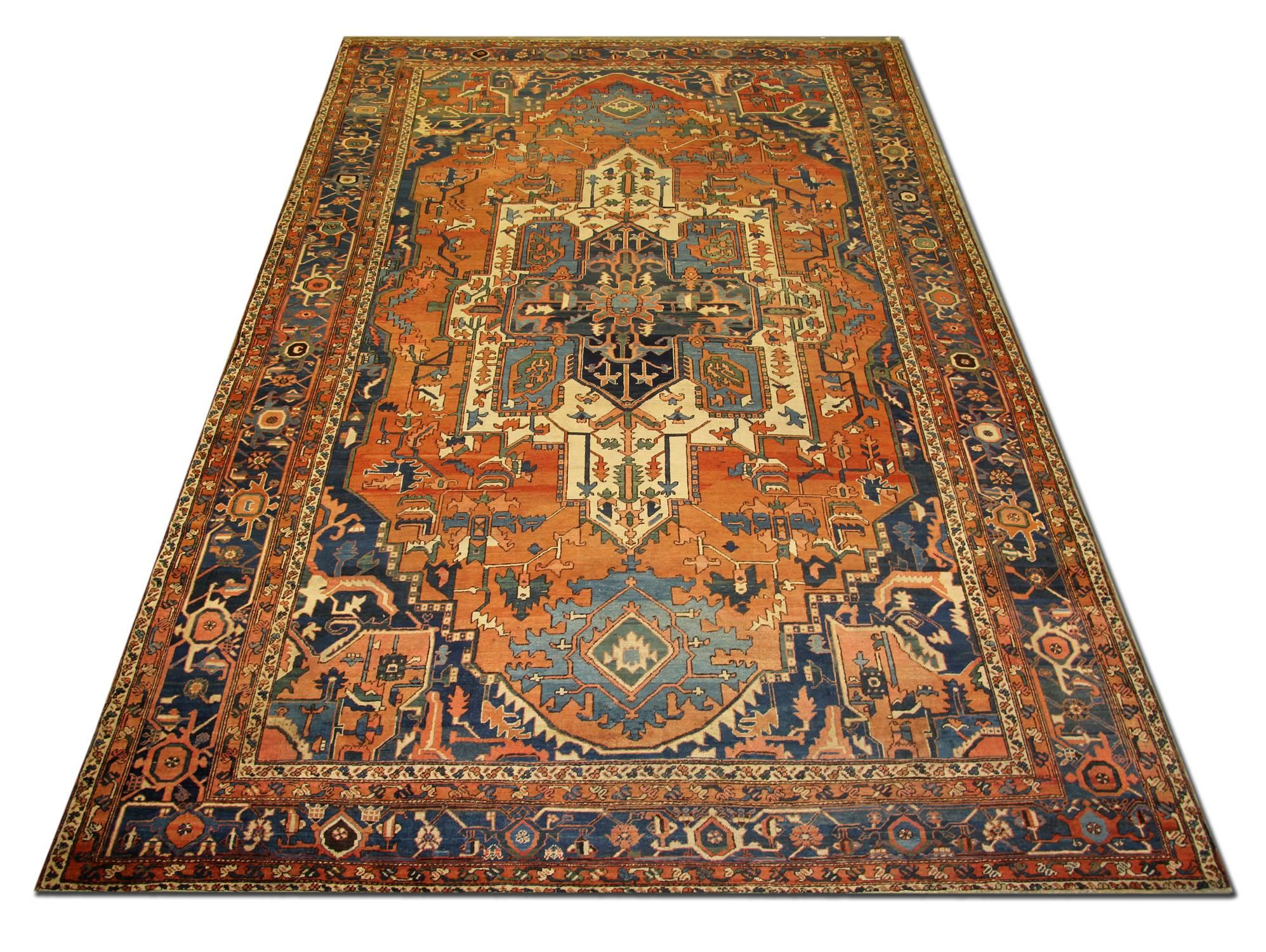 This stylish Serapi carpet rug paints a classic Persian central medallion format with saturated contrasting colour. The dark indigo internal medallion on the Persian carpet inside the bigger ivory medallion paired with a leading border of the same