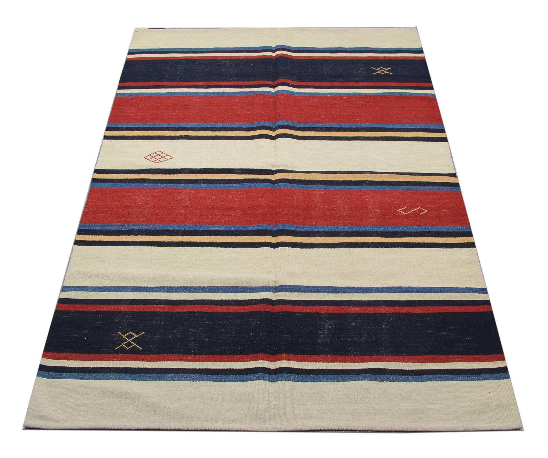 This fine wool area rug has been woven in cream, red and blue accent colours and features a simple striped design with scattered geometric motifs throughout. Both the simple colour and design in this piece make it suitable for both classic and