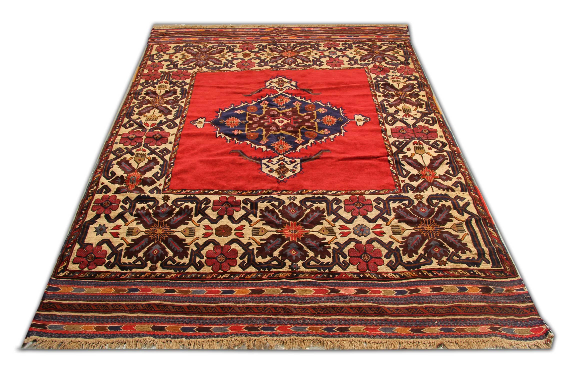 Dieser Wollteppich wurde 1970 in Afghanistan handgeknüpft. Es zeigt ein sehr detailliertes Medaillon in der Mitte, das auf rotem Hintergrund gewebt ist. Dieses wird von einer dekorativen, sich wiederholenden Blumenmuster-Bordüre eingefasst. Die
