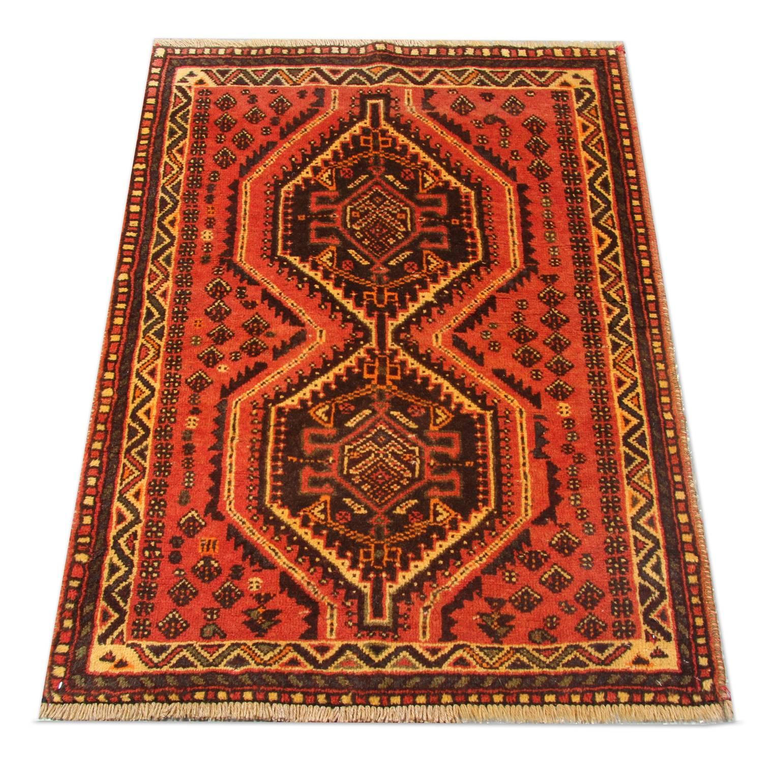 This tribal area rug has been woven by hand in Turkey and features a fantastic tribal design. Two medallions decorate the central design woven in brown, blue, orange and cream accent colours on a rich red background. This is then enclosed by a