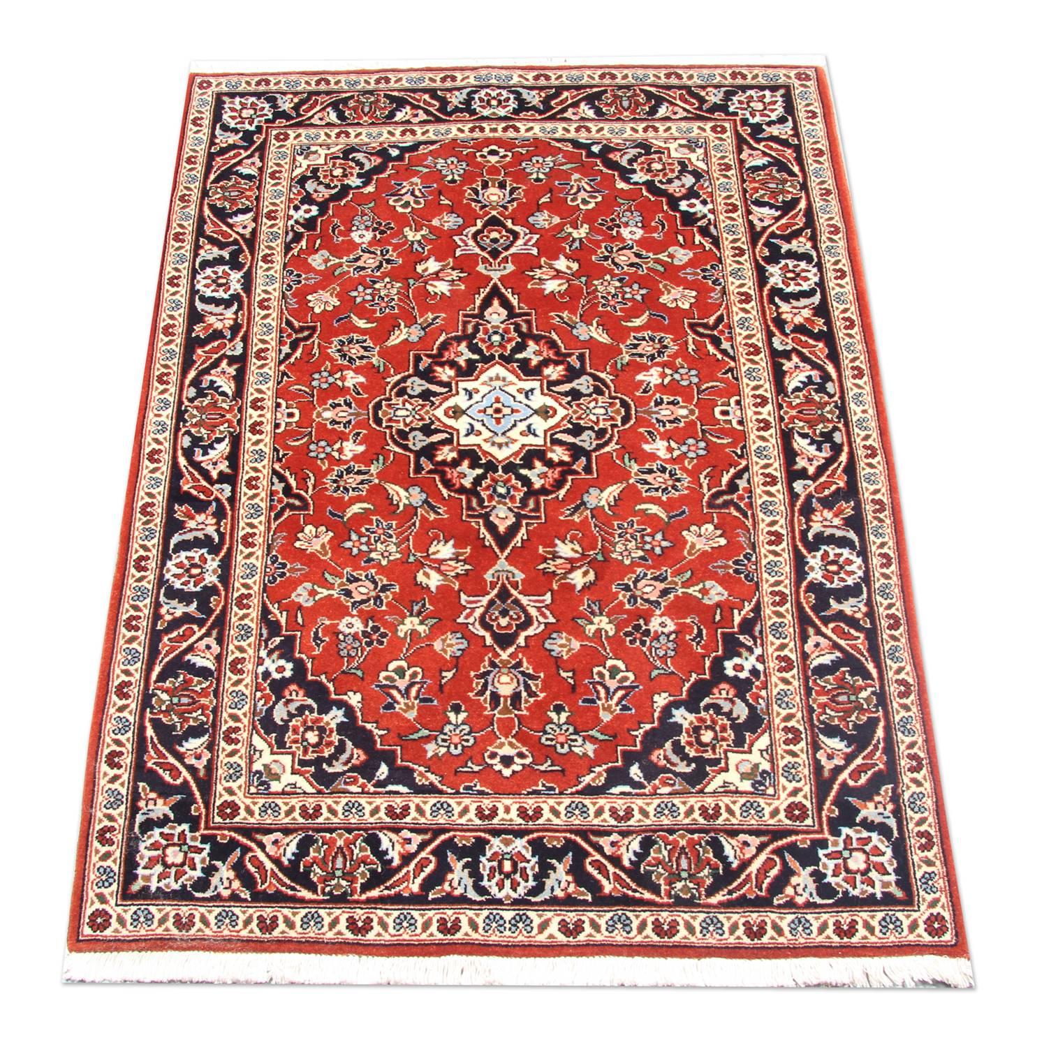This fantastic wool rug was woven by hand in Turkey in the 1950s and features a traditional medallion design. Woven with a beautiful rich red background with accents of blue, cream, beige and white that make up the delicate floral medallion and