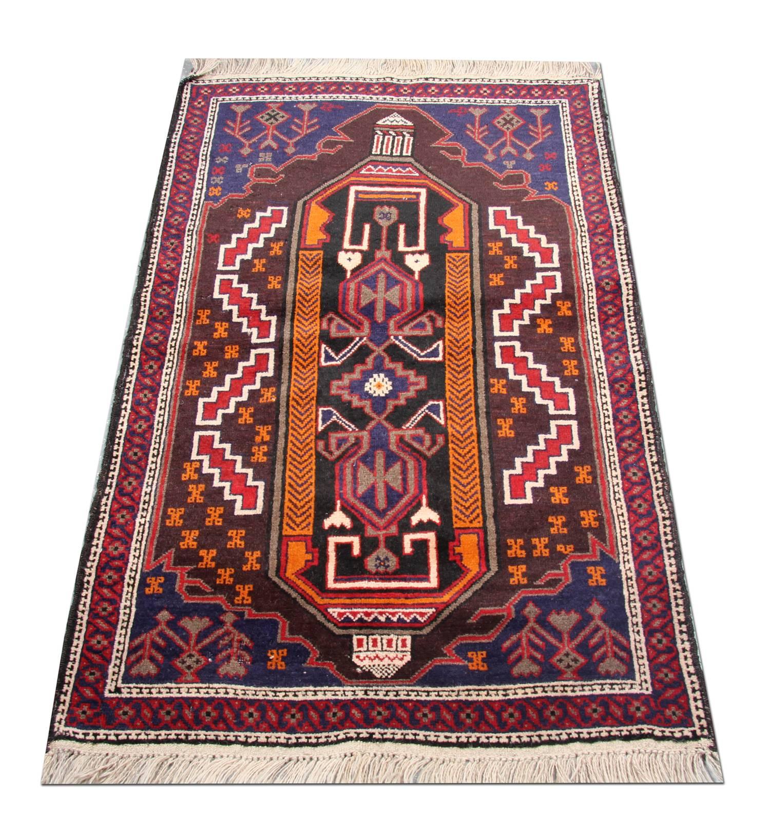 This piece was woven by hand in Afghanistan with a fine symmetrical design. The central pattern is a tribal design woven on a dark background with orange, red and white accent colors. Intricately woven with sophisticated patterns and emblems