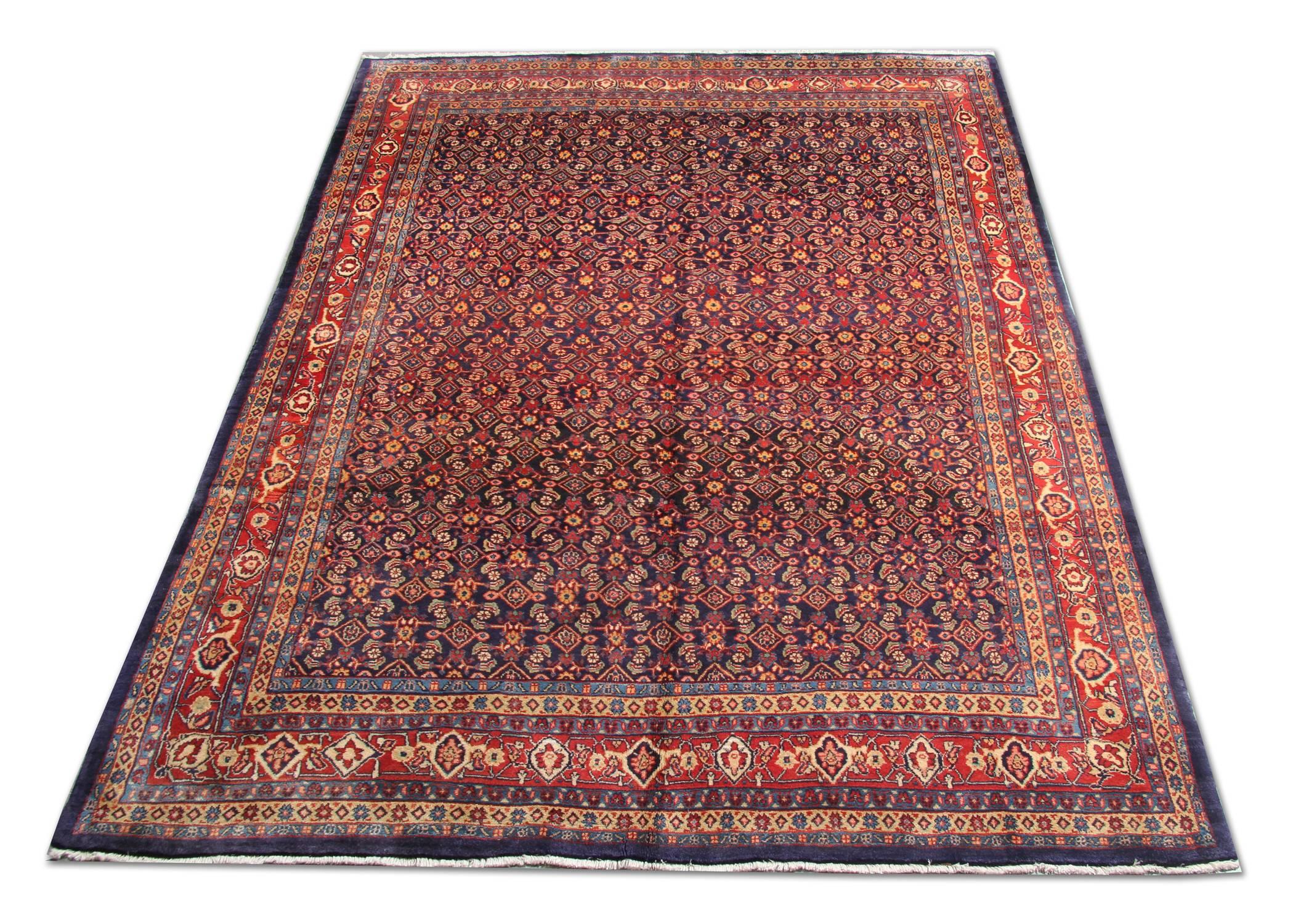 This wool rug was woven by hand with the finest organic wool in the 1990s. The central design features an intricate all-over design with a deep blue background decorated with red, yellow, green and cream accents that make up the decorative pattern.