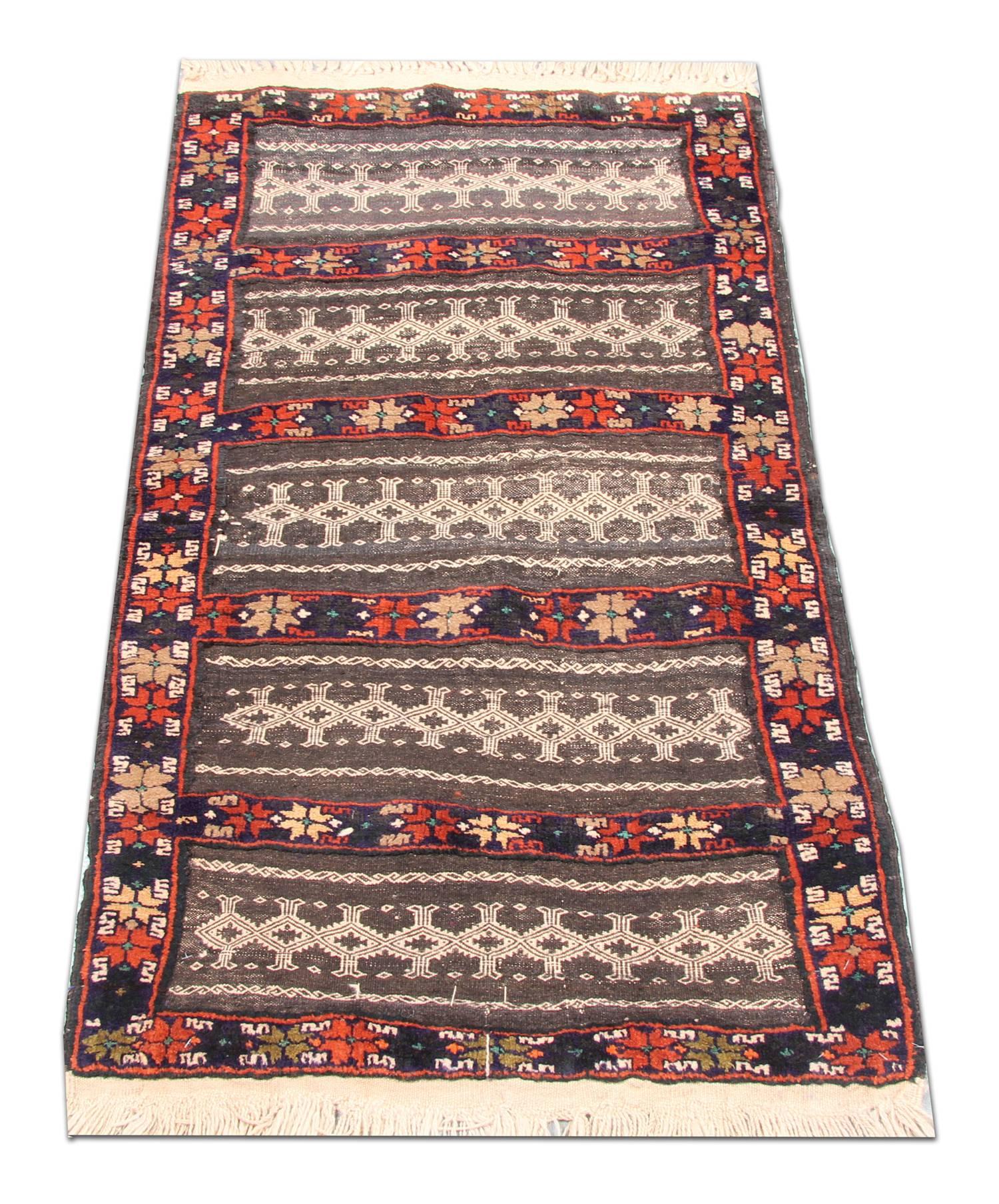 This traditional striped area rug has been intricately woven by hand. The central design features delicate symmetrical motifs with a mix of cream and brown stripes and red, blue and cream geometric pattern stripes. This is then framed by the same