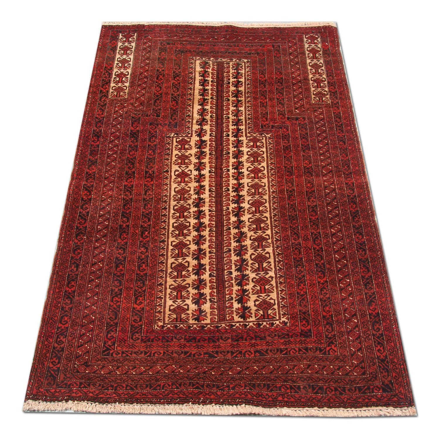 This rich red area rug was woven by hand and features a traditional prayer rug design. The central pattern reveals decorative motifs woven on a cream field in the same rich red accents as the surrounding design. This piece is sure to make the