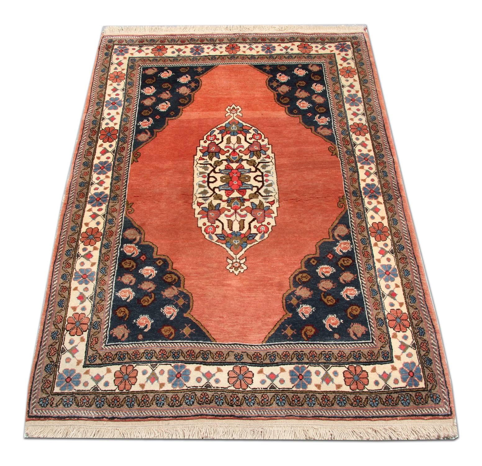 This delicate Oriental wool area rug has been woven by hand and features an open pink field with a large oval medallion which has been intricately woven in accents of green, blue and pink on an ivory background. This has been framed by a decorative