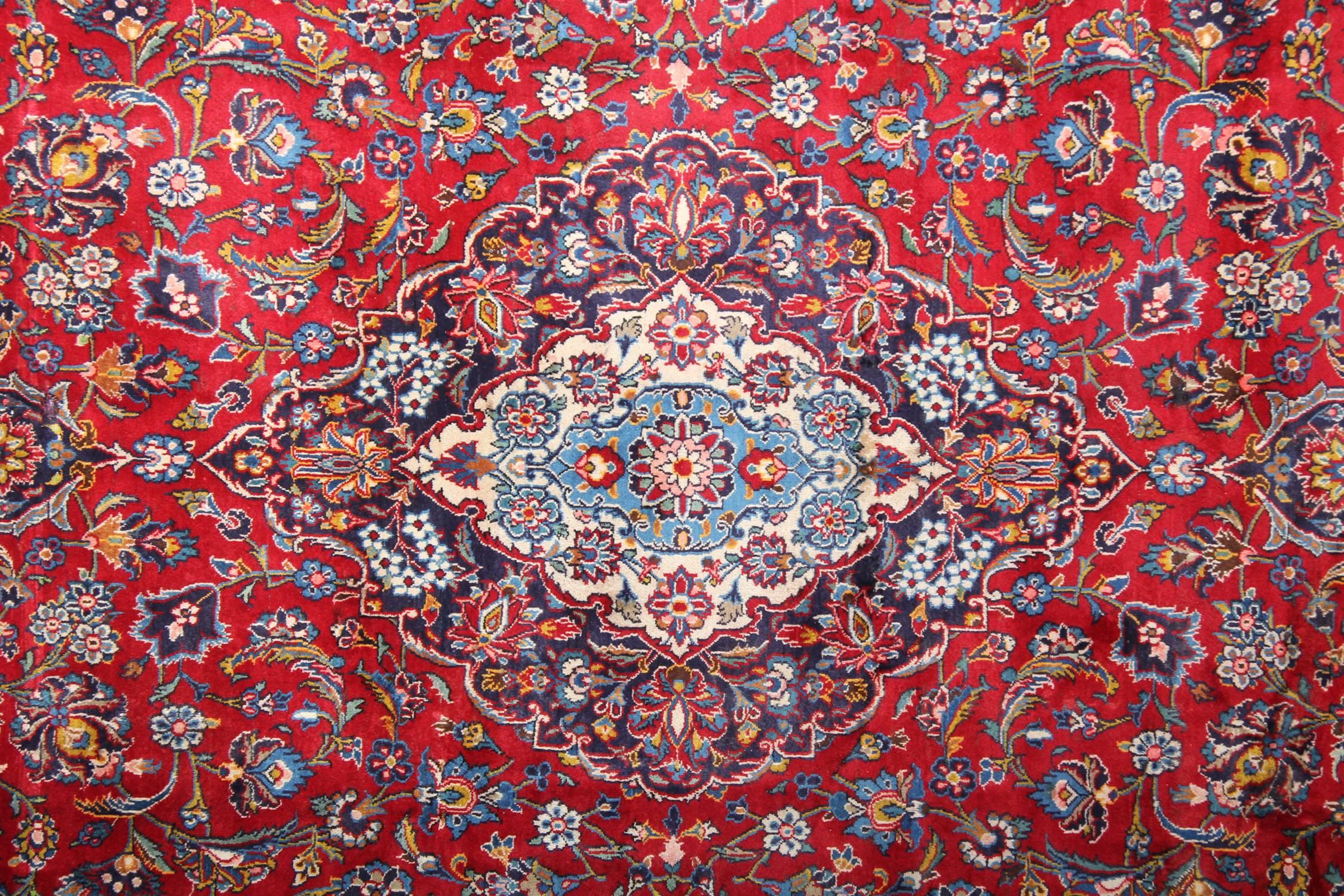 This fantastic wool rug was woven by hand in Turkey in the 1950s and features a traditional medallion design. Woven with a beautiful rich red background with accents of Blue, cream, beige and white that make up the delicate floral medallion and