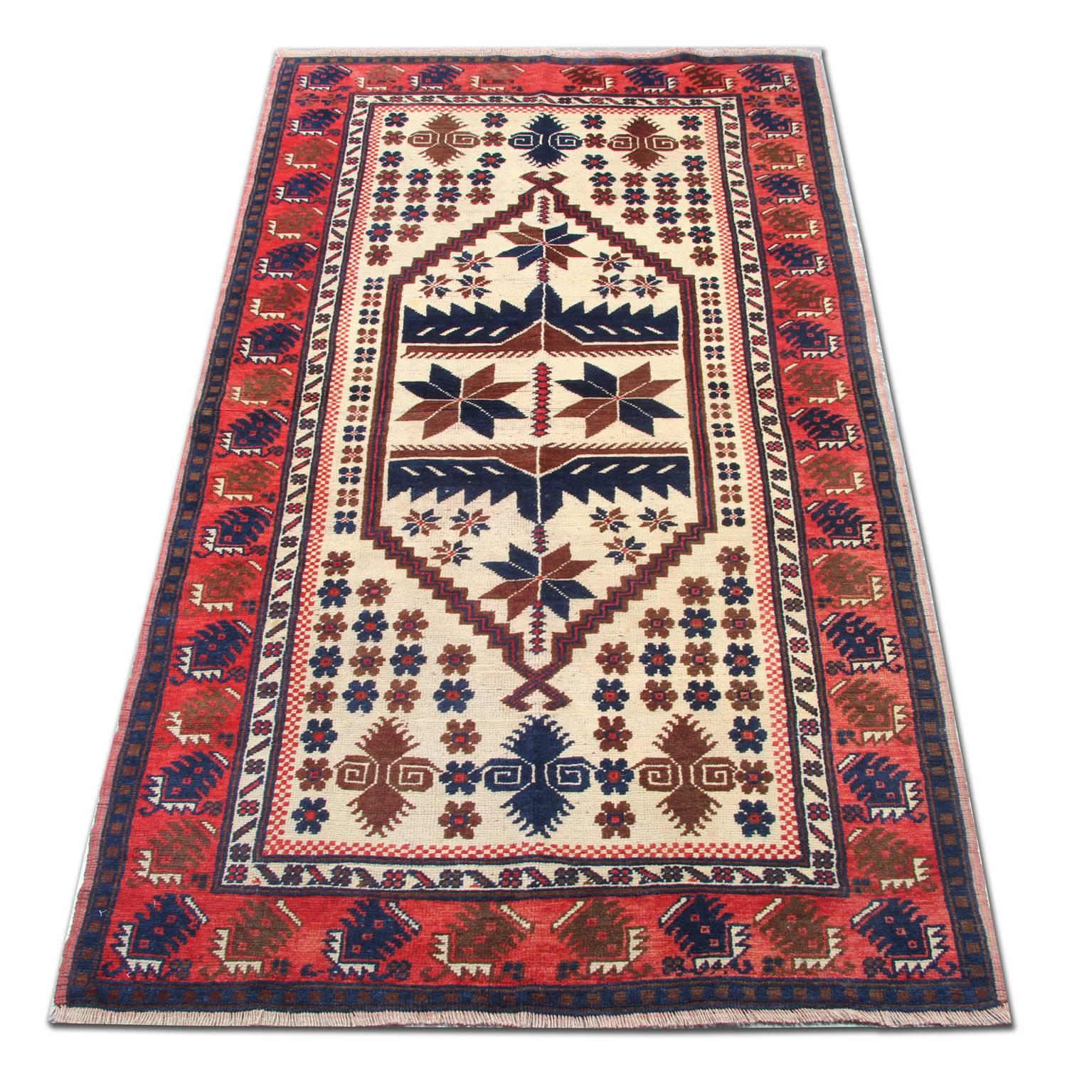 This geometric wool area rug was woven by hand with a fantastic tribal village design. The central pattern features a cream background with medallions that have been incorporated in accents of beige and deep blue. This is then enclosed with a