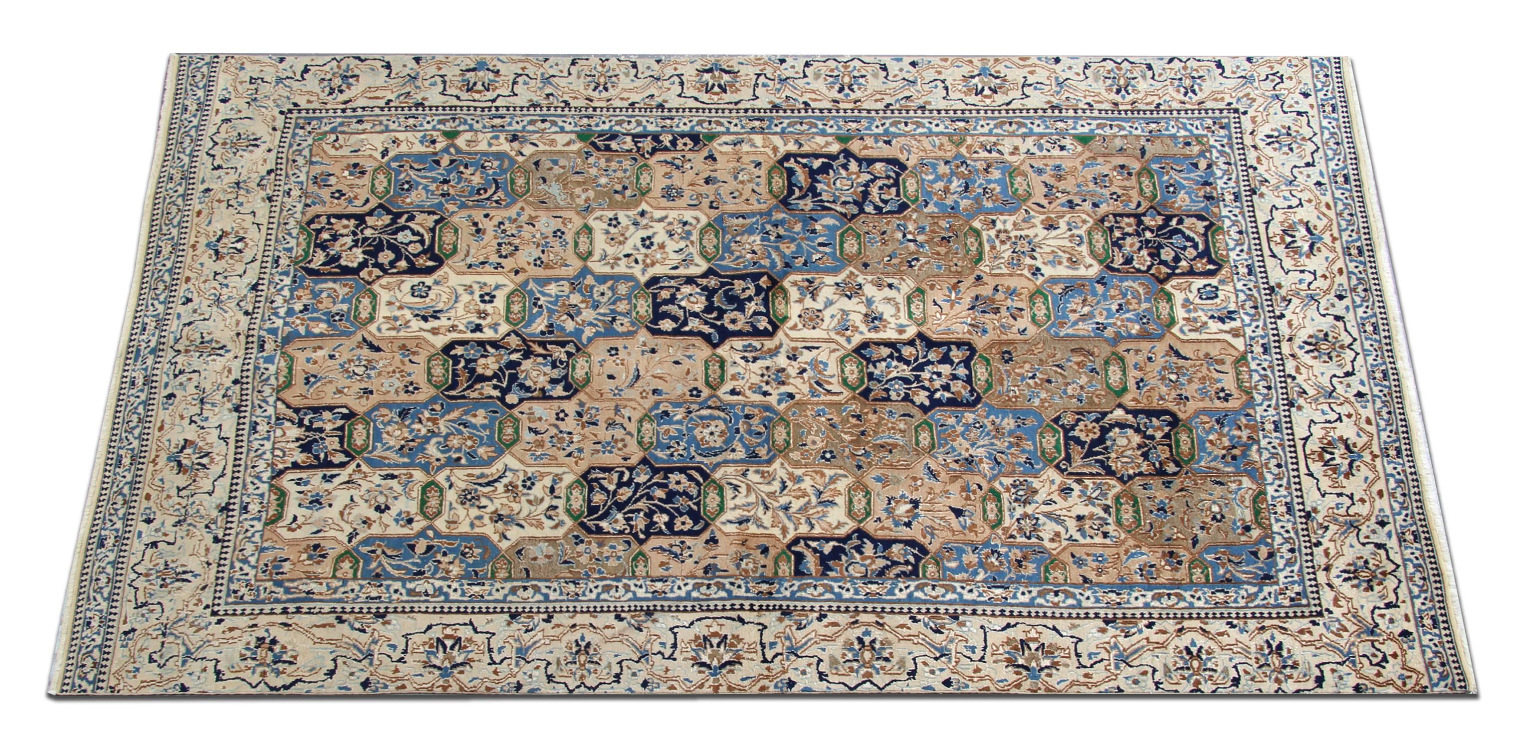 Handwoven with fine wool and a sophisticated color palette including blue cream and beige. The central design features a tile effect pattern with floral and geometric motifs, this is then framed by a decorative border which encloses the design. The