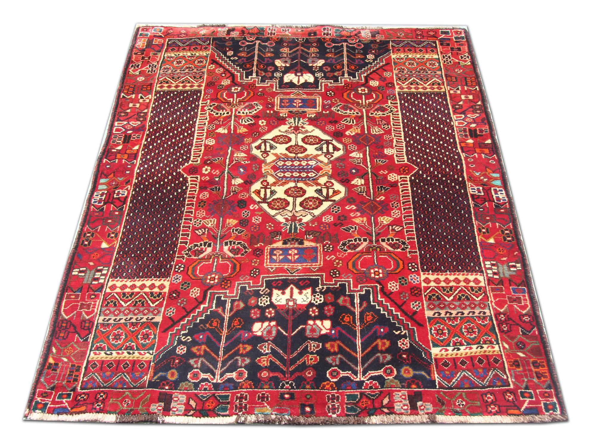 This beautiful wool rug features a fantastic symmetrical tribal design. They are woven in accents of blue and cream on a red field. This rug is adorned with highly-detailed motifs and medallions and is sure to uplift any carpeted tiles or hardwood