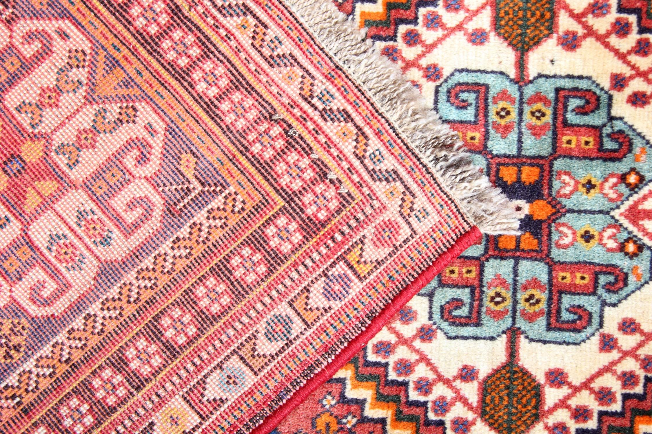 This fine wool rug was handwoven in 1960 it features a highly detailed tribal design. Woven on a red field accents of beige cream and blue have been used to create beautiful diamond central medallions. Surrounded by floating motifs and intricate