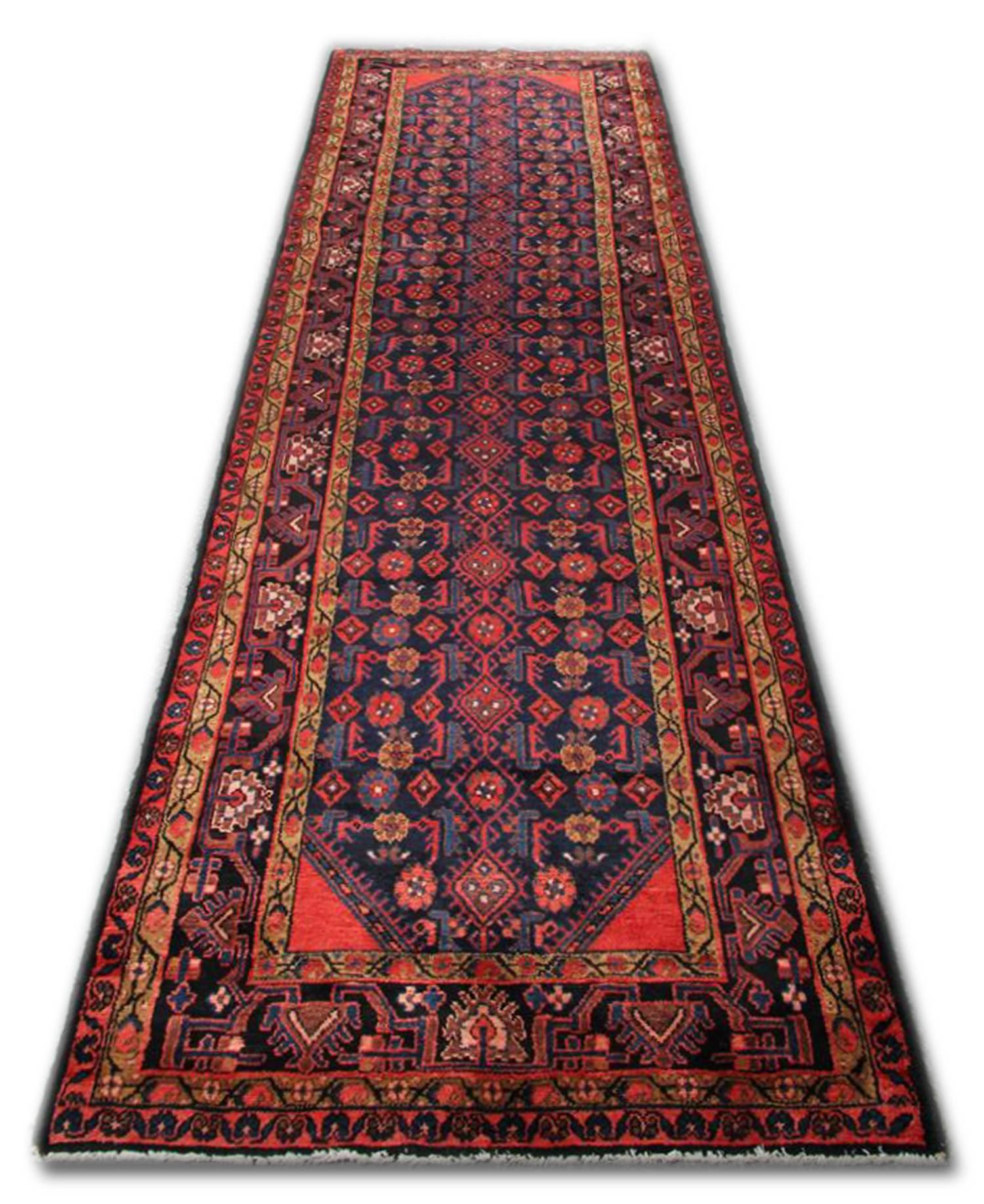 This beautiful wool rug was handwoven in Afghanistan in 1950. This beautiful wool rug features a red background with an intricately woven repeat pattern with a highly detailed layered border. Both the colour and design in this wool rug make it the