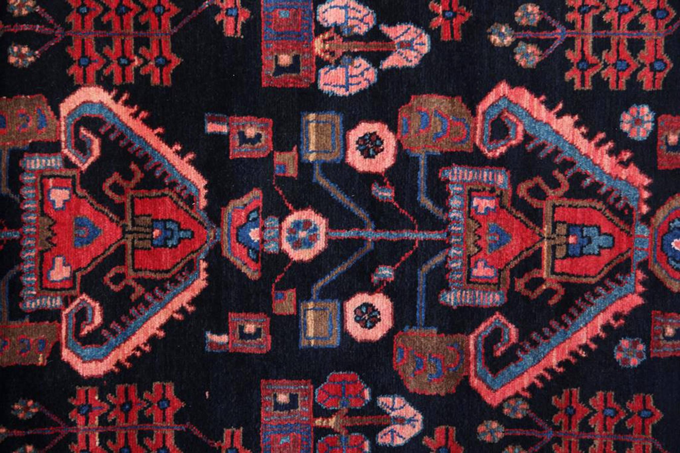 This elegant wool rug was woven by hand in the 1950s with a fantastic geometric repeat pattern design. The central pattern has been woven on a dark background with contrasting red, blue and beige accents that make up the decorative tribal design. A
