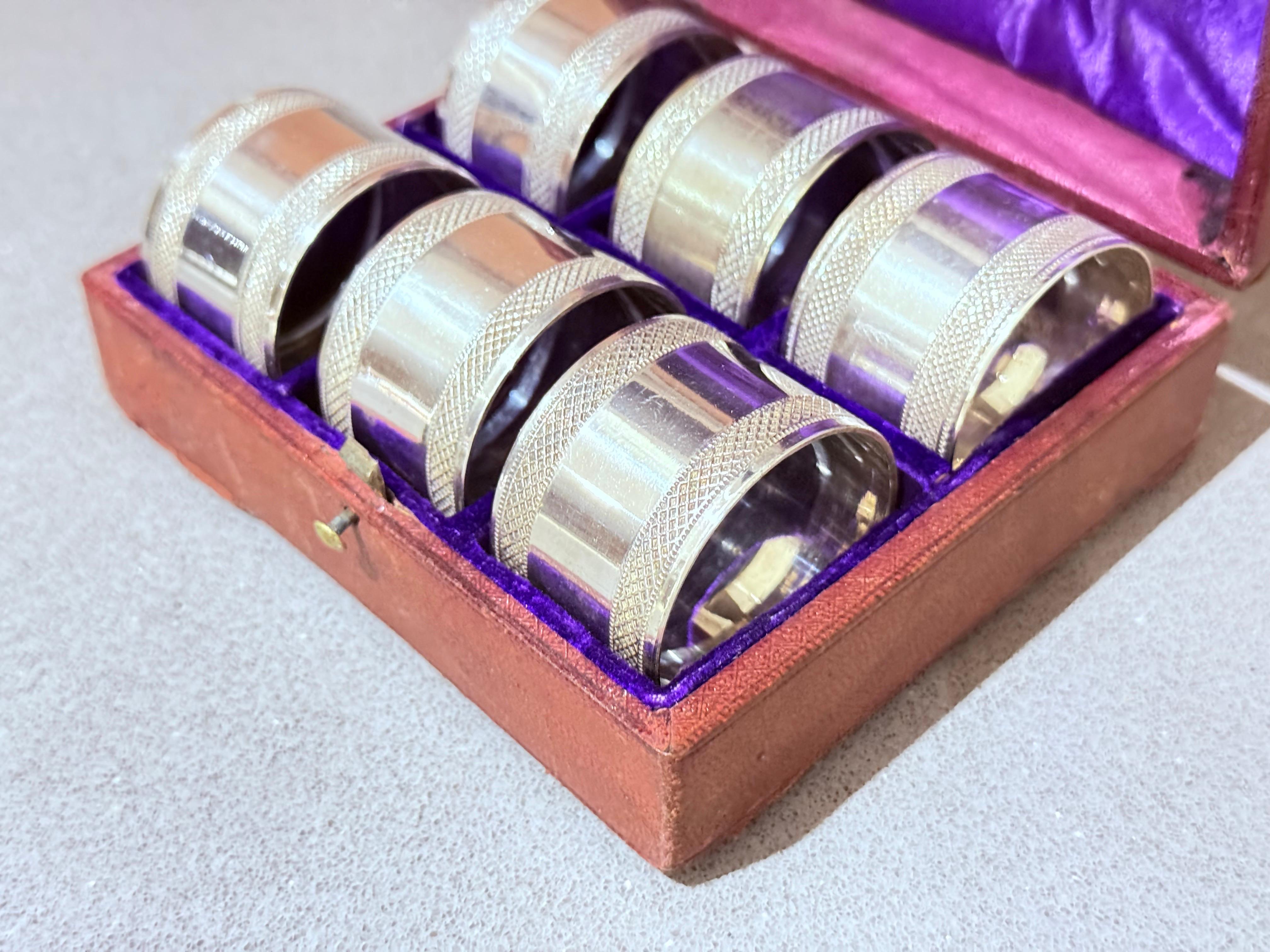 Eleganza per la tua esperienza culinaria con questo elegante set di 6 portatovaglioli antichi inglesi placcati in argento, splendidamente presentati nella loro custodia originale foderata in velluto. Ogni anello è finemente inciso con un motivo