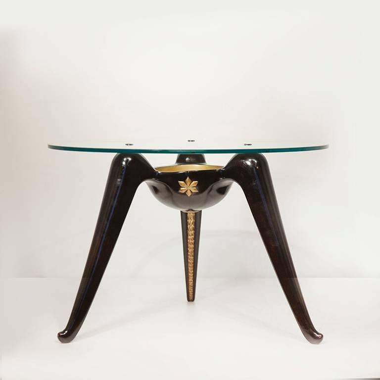 Coffee table by Osvaldo Borsani, in ebonized mahogany with carved and gilt details to the base and glass top, Aterlier di Varedo, Italy, circa 1937.

Literature: Irene de Guttry, Il Mobile Italiano Degli Anni Quaranta e Cinquanta, Rome, 1992, P.