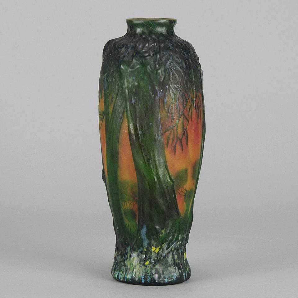 An impressive mould blown cameo glass vase decorated with an atmospheric forest scent, the foreground represented with deep green trees, their thick trunks surmounted with cascading leaves, the background with a fiery sunset sky and further forest