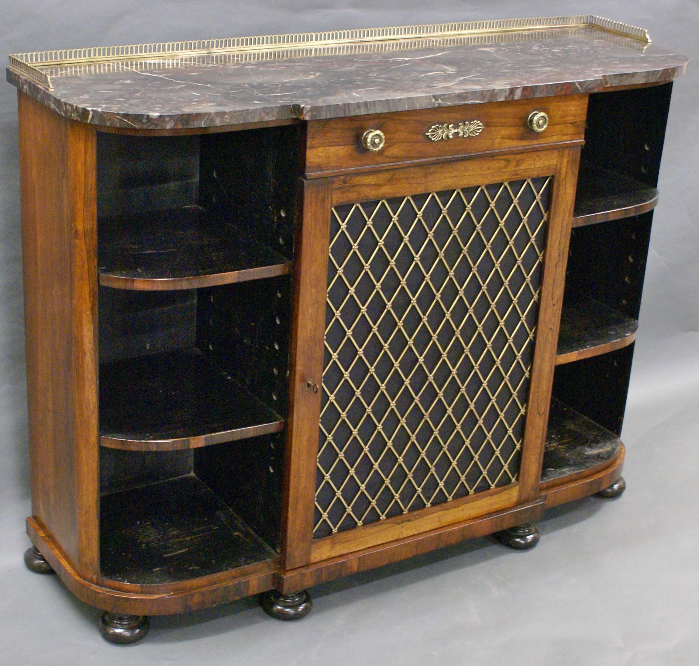 Standing on turned and ebonized feet, with central door with brass grille behind which are 2 adjustable shelves, above is a single drawer with original knobs an Anthemion decoration. On either side are curved 