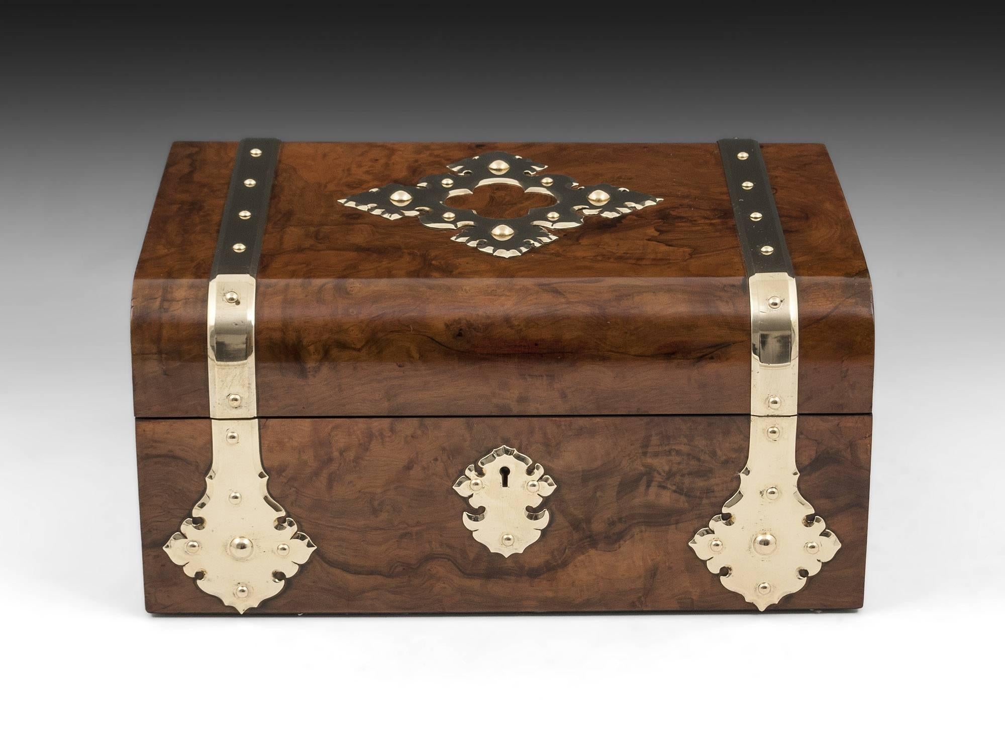 Antique Games Compendium veneered in Olive wood with ornate brass straps running from front to back, with matching ornate escutcheon. 

The antique games box interior is lined in red leather and blue watered silk, incorporating a red leather chess