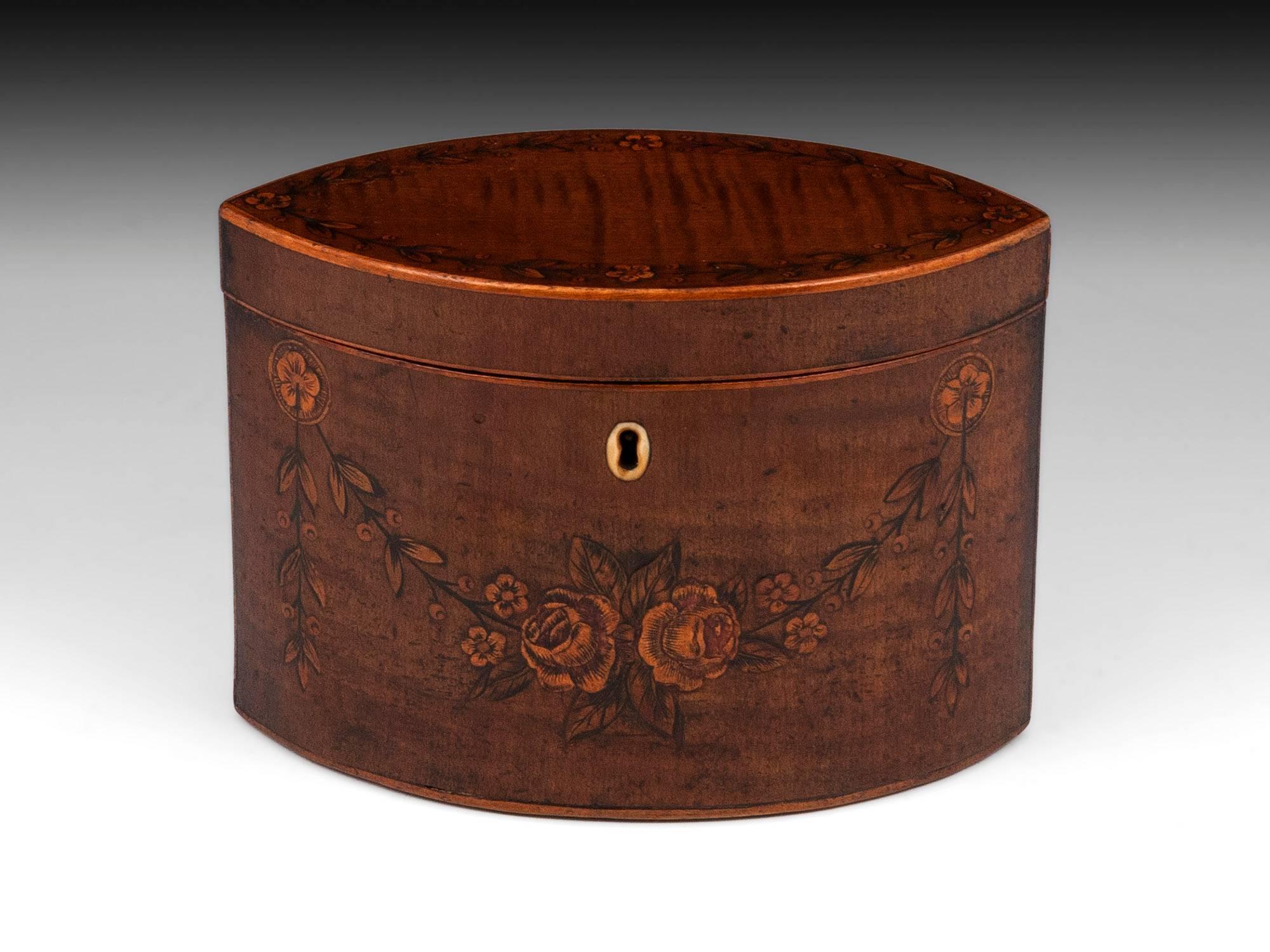 Harewood navette shaped tea caddy adorned with inlaid engraved flower garlands and bone escutcheon.

The navicular tea caddy's interior features a floating lid with brass handle, and contains traces of its original tin lining. 

This Georgian
