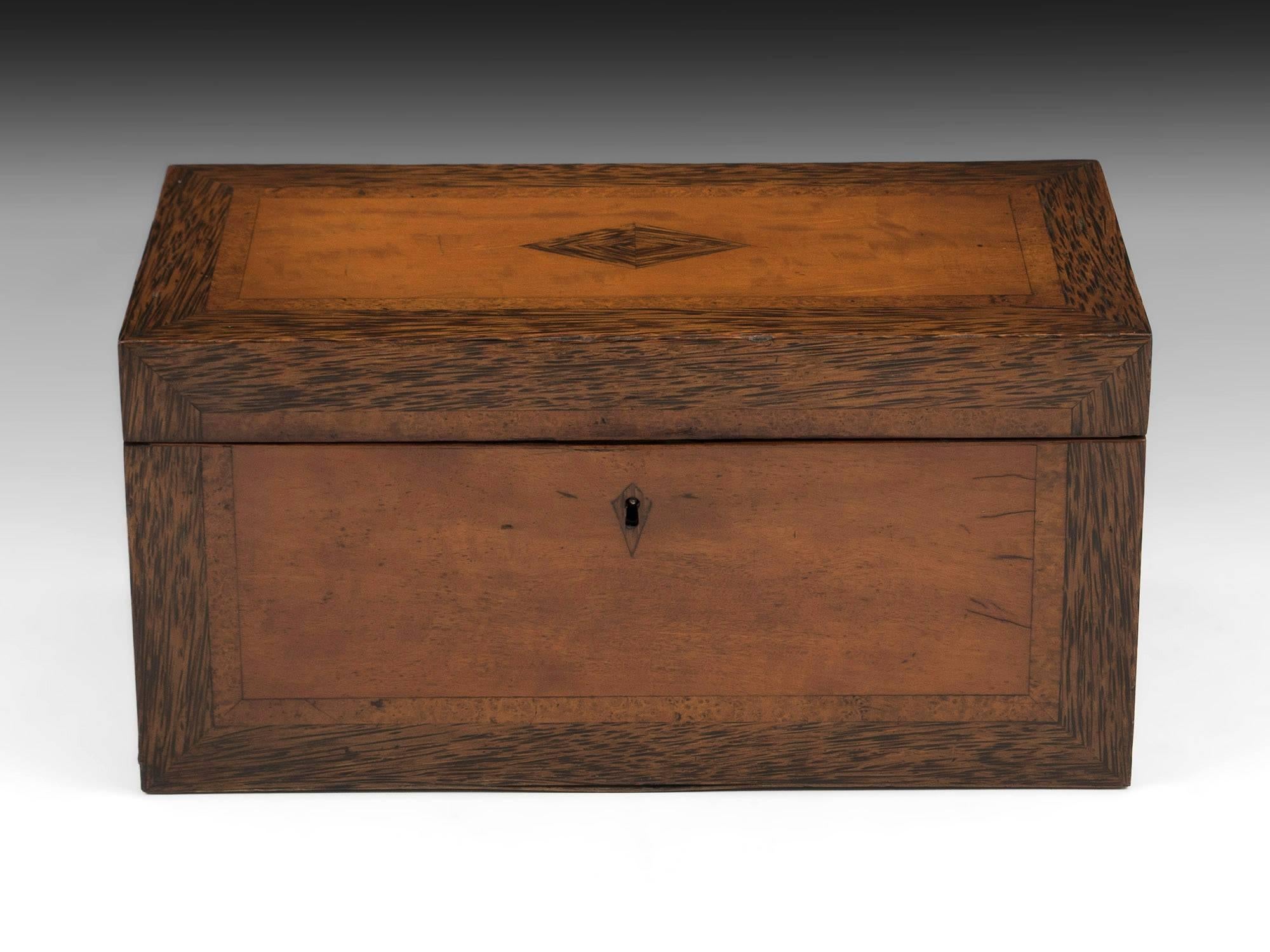 Satinwood tea chest with coconut wood mitred edging on all sides along with a framed amboyna inlay. 

The exotic satinwood tea chest interior features two removable tea caddies with coconut wood edging to match the exterior and each tea caddy is