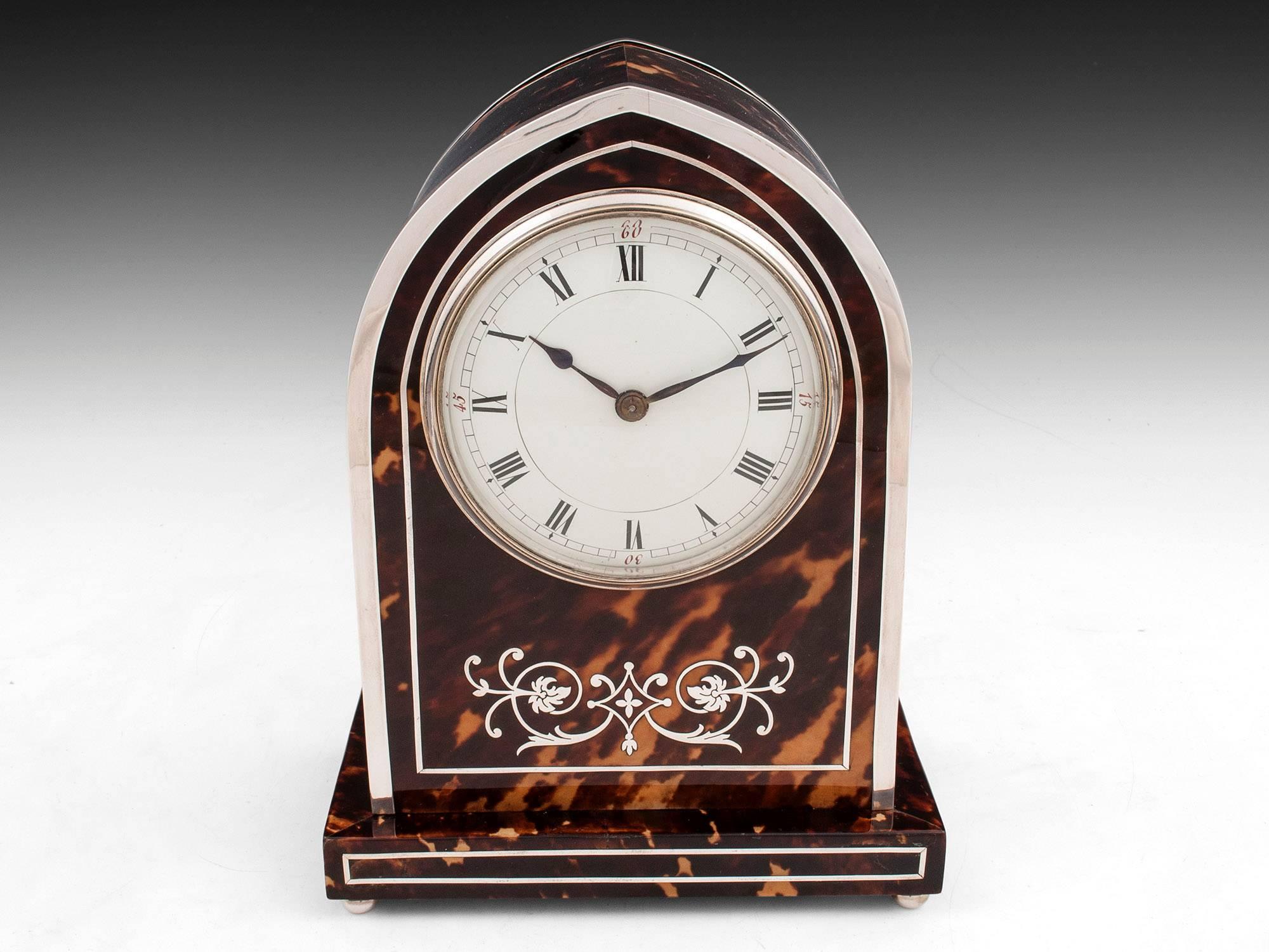 An exquisite silver inlaid tortoiseshell Gothic arched clock with silver banding and mesh panels to the side, standing on silver ball feet. Hallmarked Birmingham 1905 by Douglas Clock Co. 

Has eight day French movement which has been recently