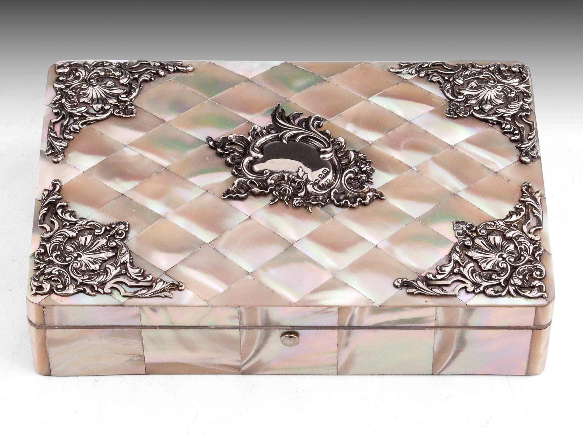 A mother-of-pearl jewelry box with amazing patternation and color to the shell. The top with silver monogram cartouche and mounts dated Birmingham 1896 by Pearce & Thompson. The interior is lined in its original green crushed silk to the lid. 