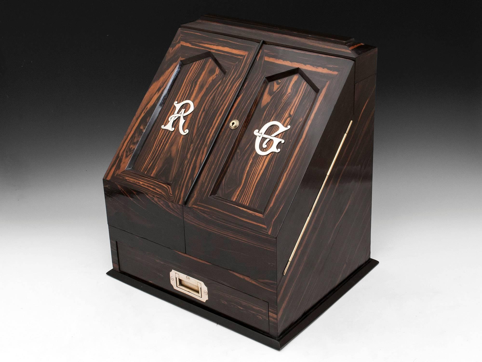 Antique stationery cabinet veneered in sumptuous and striking coromandel with silvered handled drawer to the base, monogram of R & G and Bramah lock. Opening the cabinet reveals a striking contrast interior veneered in another exotic timber,
