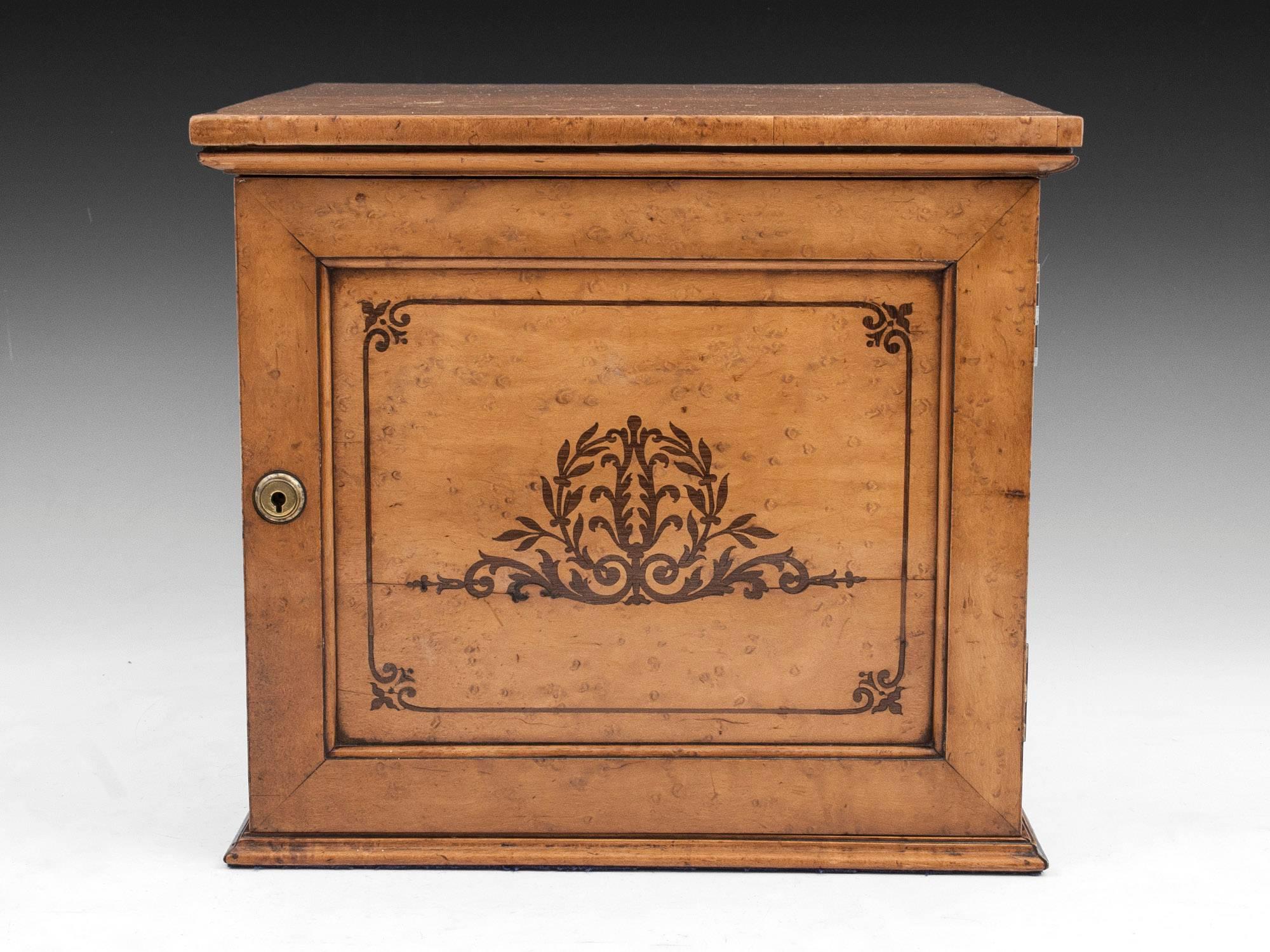 Stunning bird’s-eye maple cigar cabinet with brass escutcheon and flush carry handles. 

The interior contains three mahogany drawers each beautifully constructed using dovetail joints, the fronts having unusual brass handles and removable