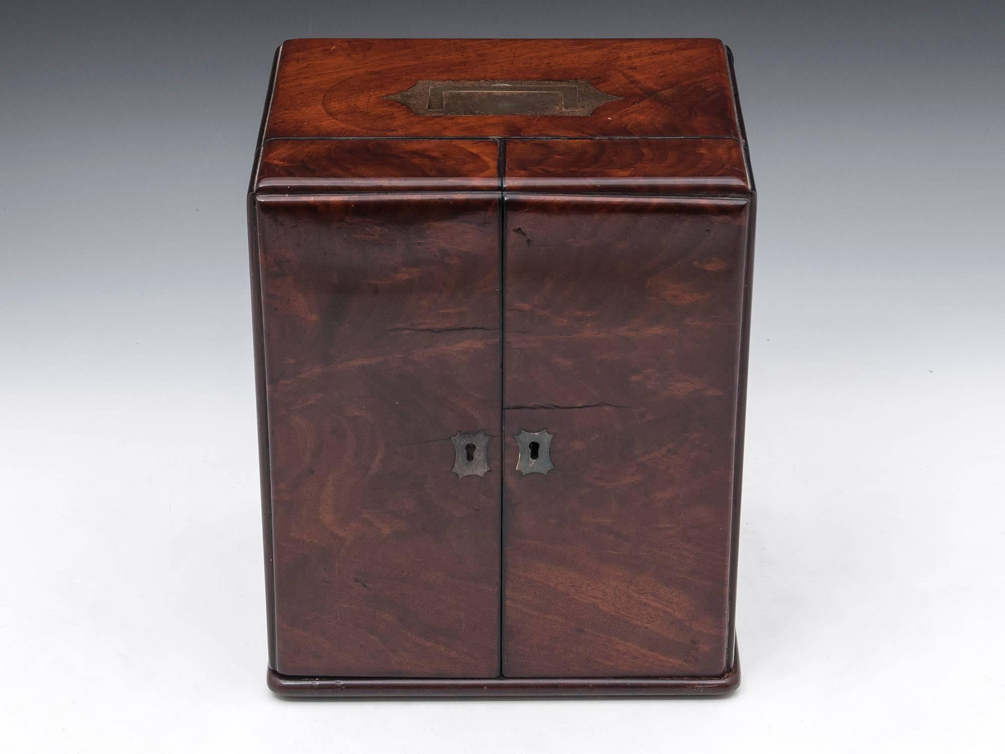Early Victorian apothecary box in beautiful flame mahogany, with a flush-fitting Campaign brass carrying handle. It has double-opening lockable doors, two fitted drawers and a secret concealed medicine compartment to the back.
 
Inset to the front