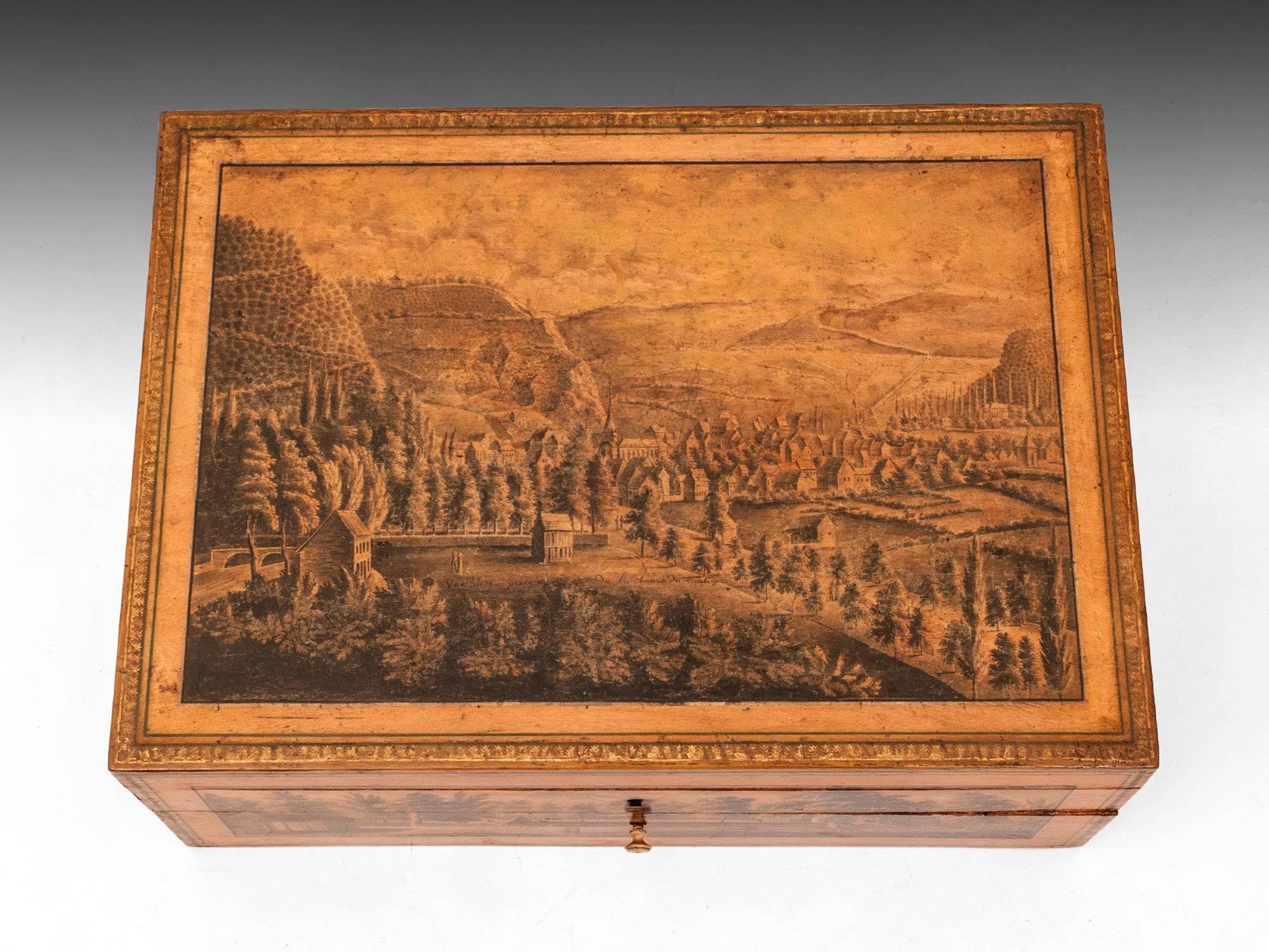 A rare and beautifully decorated spa sewing box, depicting skillfully hand-decorated scenes around the Belgian town of Spa in the Ardennes mountains. Each detailed scene is framed with two single green lines, with the top having a floral gold leaf