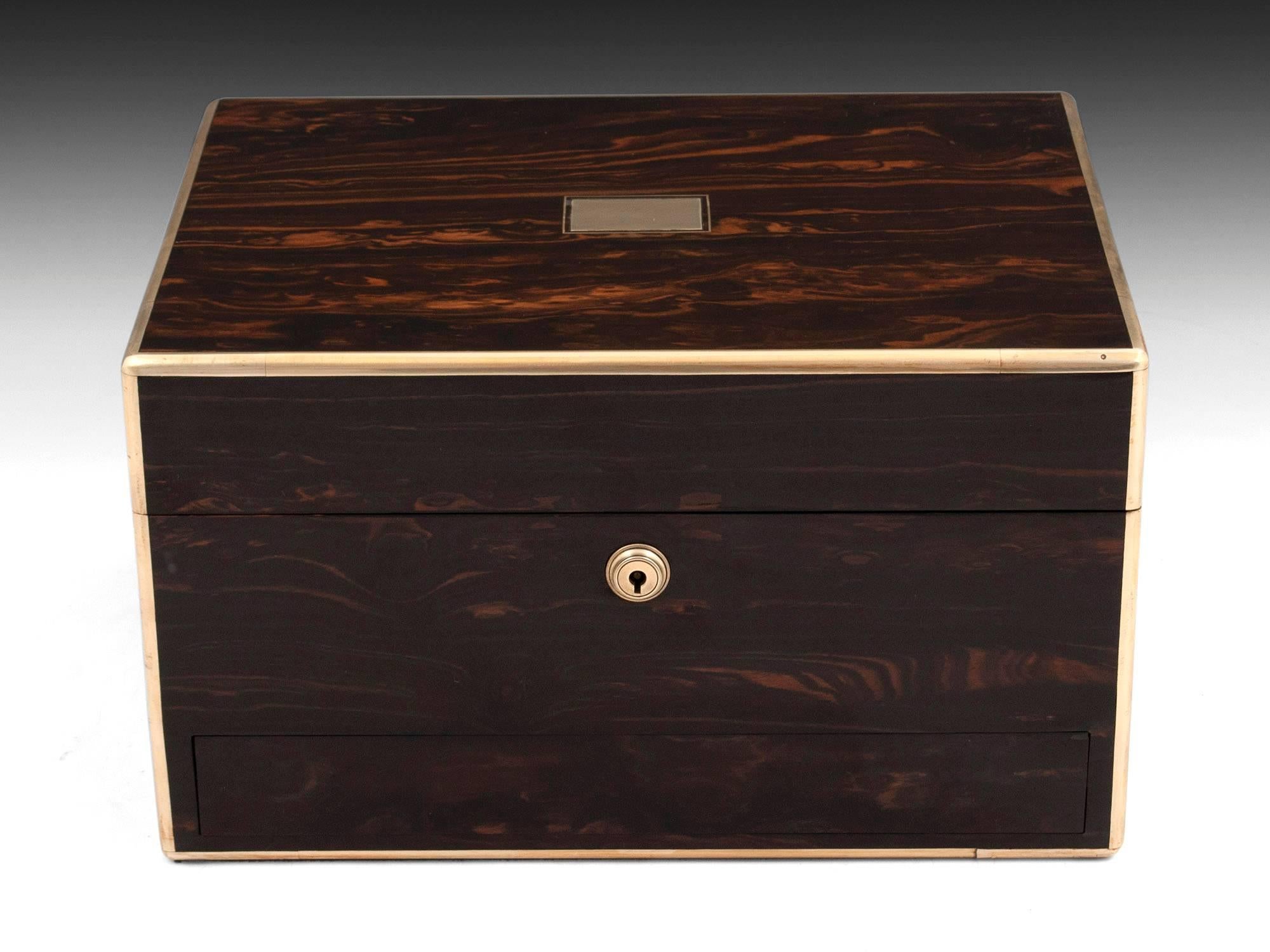 Coromandel jewellery box with brass edging, escutcheon and flush fitting carry handles. 

The interior is lined with black leather paper, with gold tooling on the edges, complemented by luxurious padded burgundy silk velvet. Featuring a removable