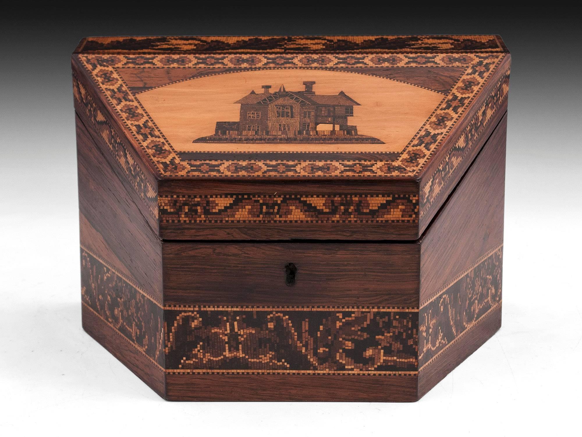 Tunbridge ware stationery box veneered in flame mahogany with an unusual Topographical Cottage design on the lid surrounded with floral bands. 
The interior of the antique Tunbridge ware box is lined with original pink and gold star patterned paper
