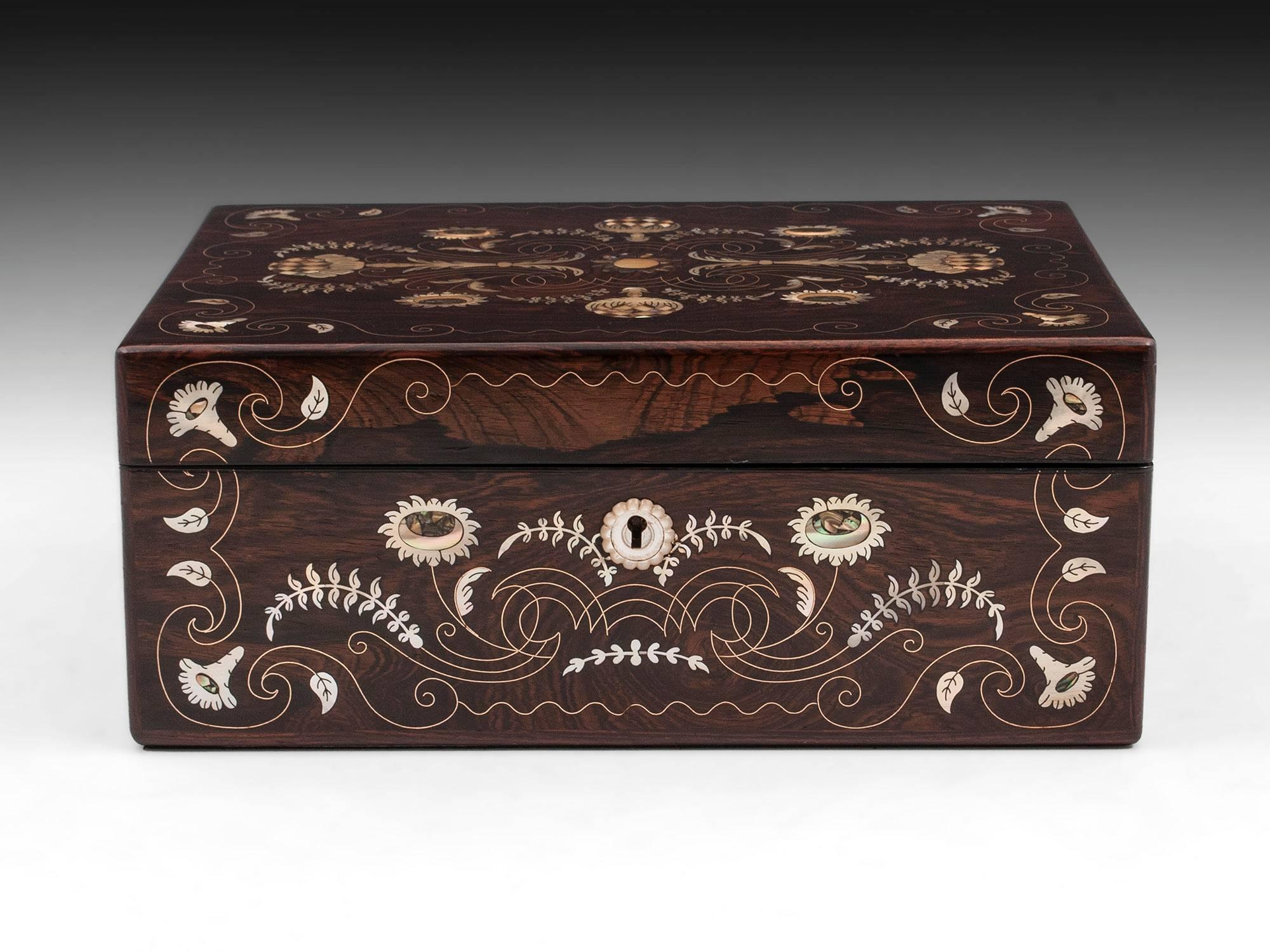 Pretty antique rosewood jewelry box with beautiful, delicate floral inlays using brass, abalone and mother of pearl, with a carved mother of pearl escutcheon.

The interior of this exquisite antique jewelry box is lined with black silk paper and