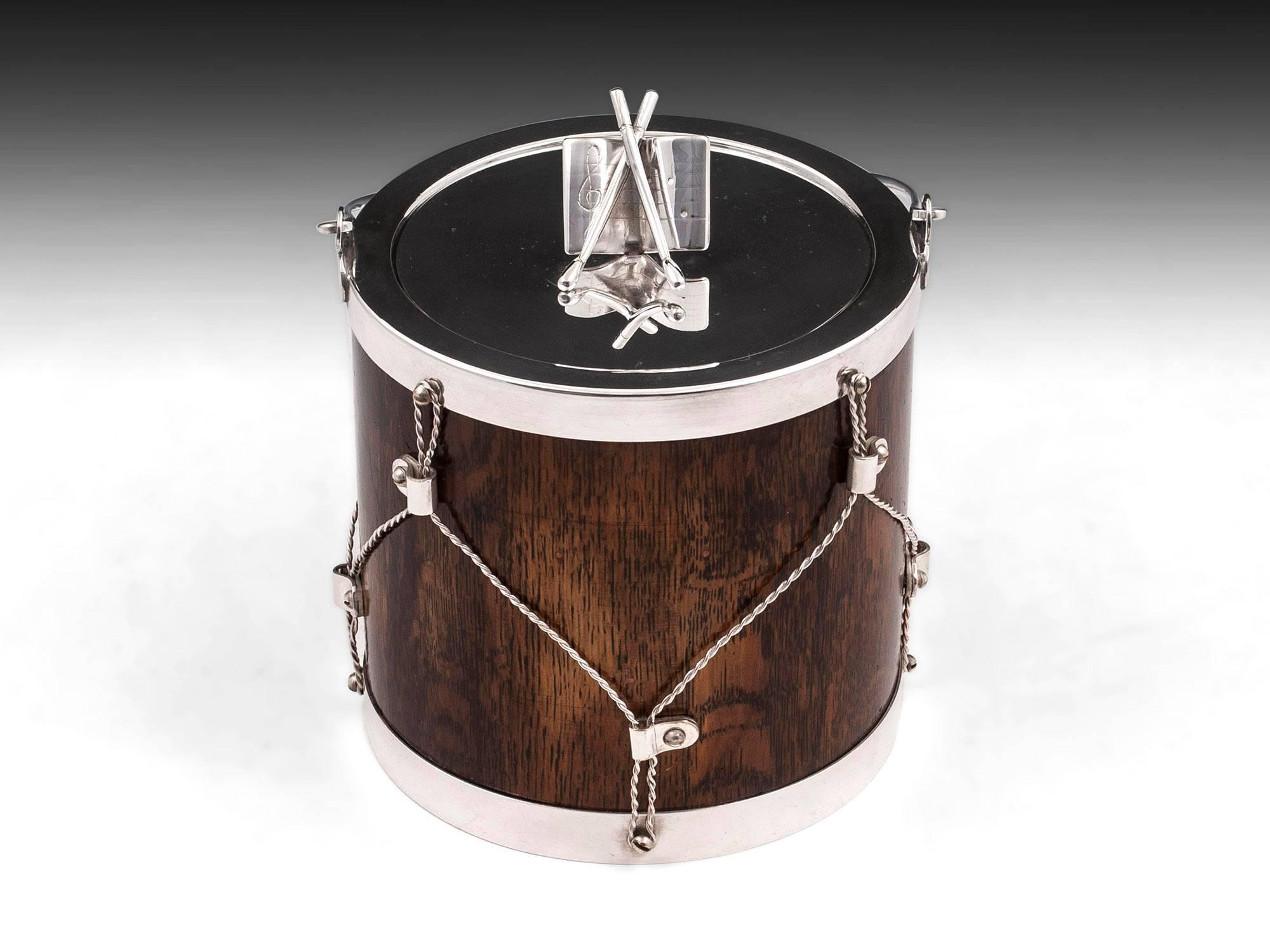 Novelty Victorian biscuit barrel in the form of a drum, made from oak and featuring silver plated details, including the removable lid which is adorned with sheet music and drumsticks. 

The interior of the military drum biscuit barrel features