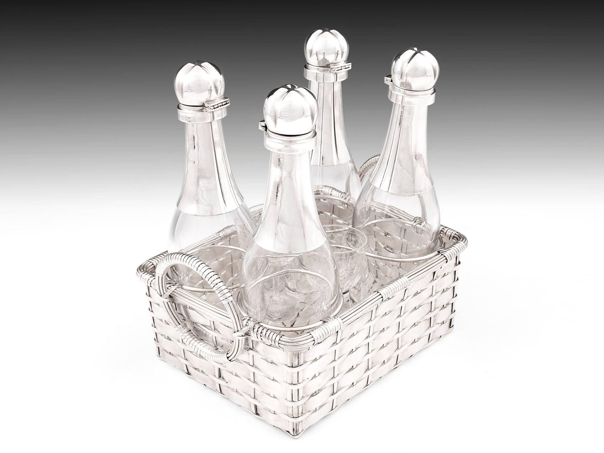 Stunning silver plated champagne bottle decanters housed in weaved basket with carry handles including two liqueur glasses. 

The four decanters have silver plated necks and caps. Lifting the hinged cap will reveal a glass stopper in each of the
