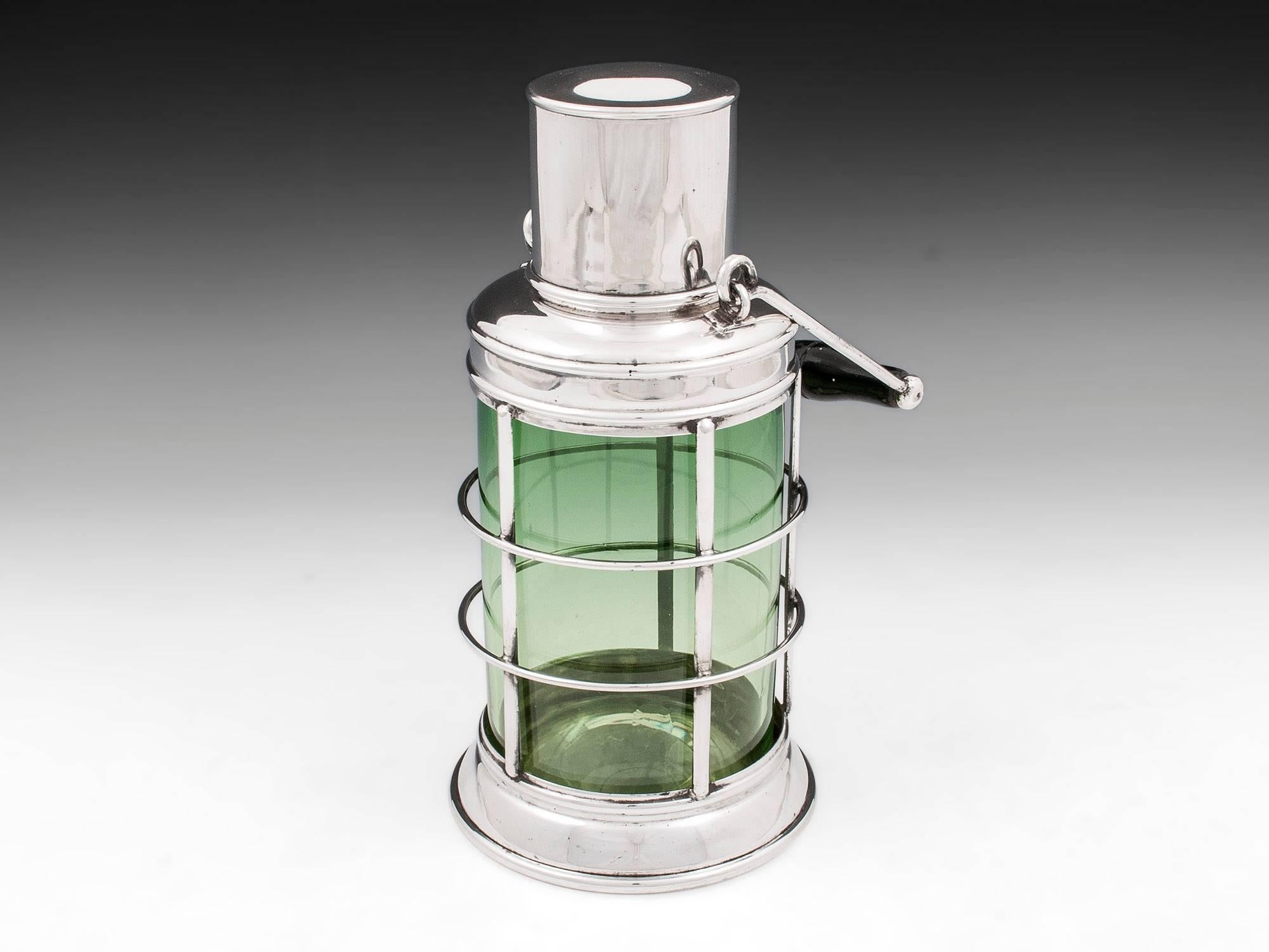 Novelty silver plated cocktail Shaker in the form of a lantern with cylindrical green glass body. Complete with wooden turned ebonized carry handle. 

The top of the lantern cocktail Shaker has cork stopper, strainer and silver plate lid.