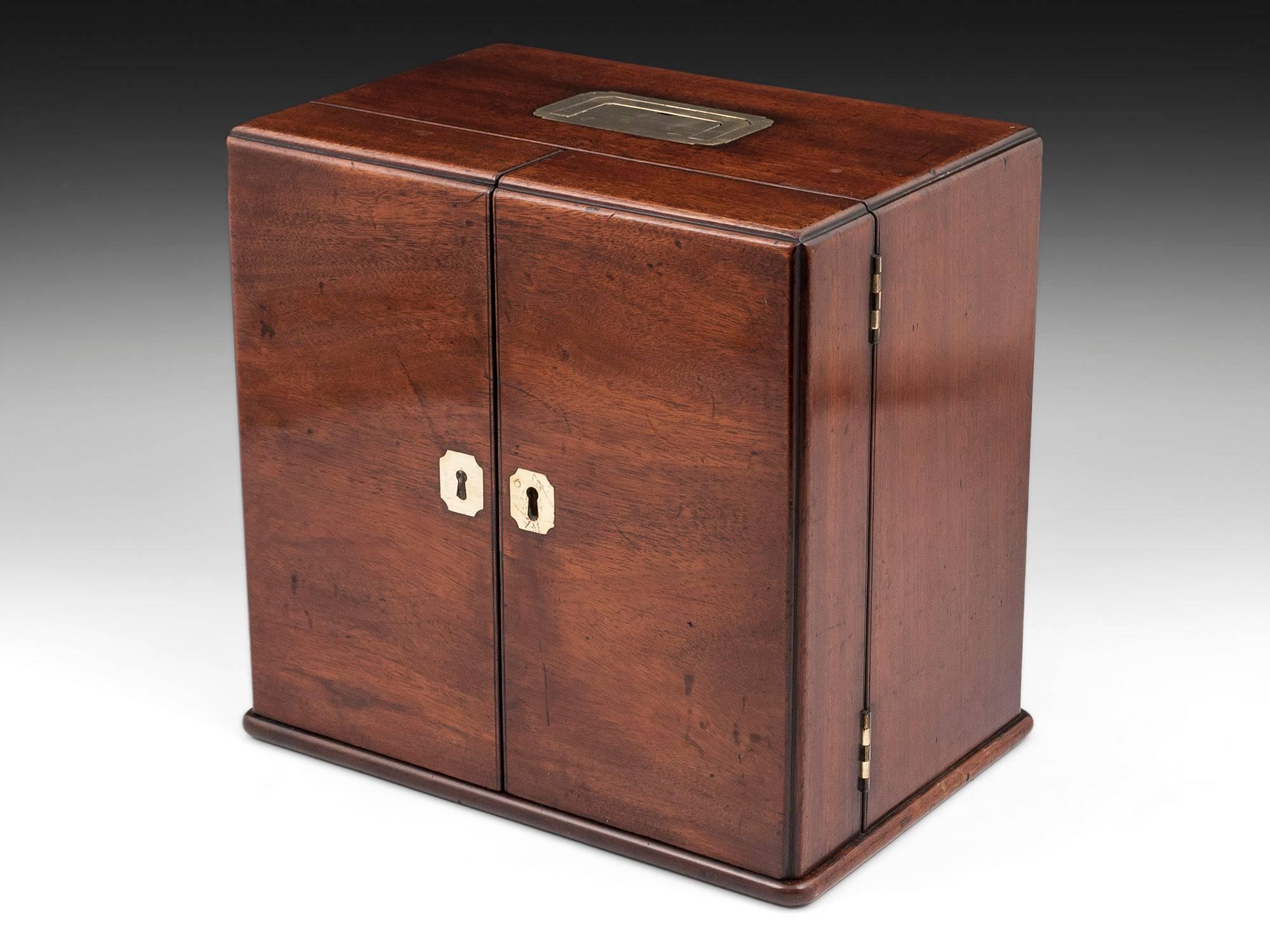 Antique Apothecary box made of solid mahogany with two brass shaped escutcheons and flush fitting carry handle to the top. 

Opening the doors of this splendid unusual apothecary box reveals twelve fitted medicine bottles housed inside the doors
