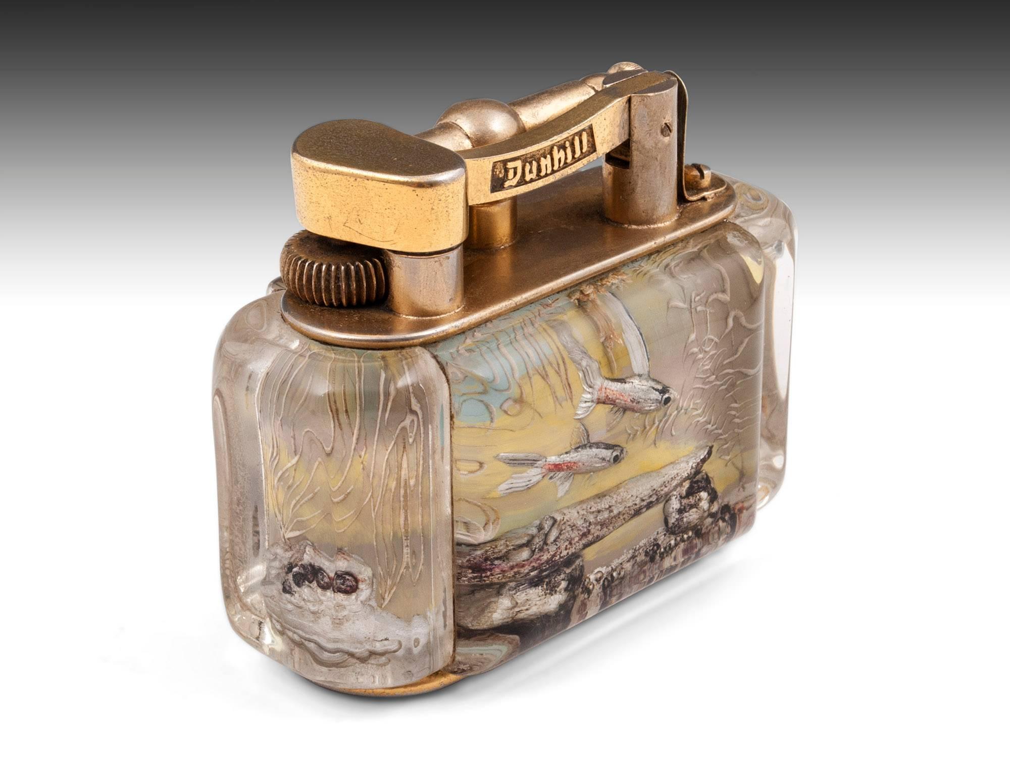 Aquarium table lighter by Alfred Dunhill. 

This "half-giant" size lighter features reverse carved and painted Lucite panels with decoration of fish swimming underwater and features a gilded mechanism with the Dunhill retailers mark.