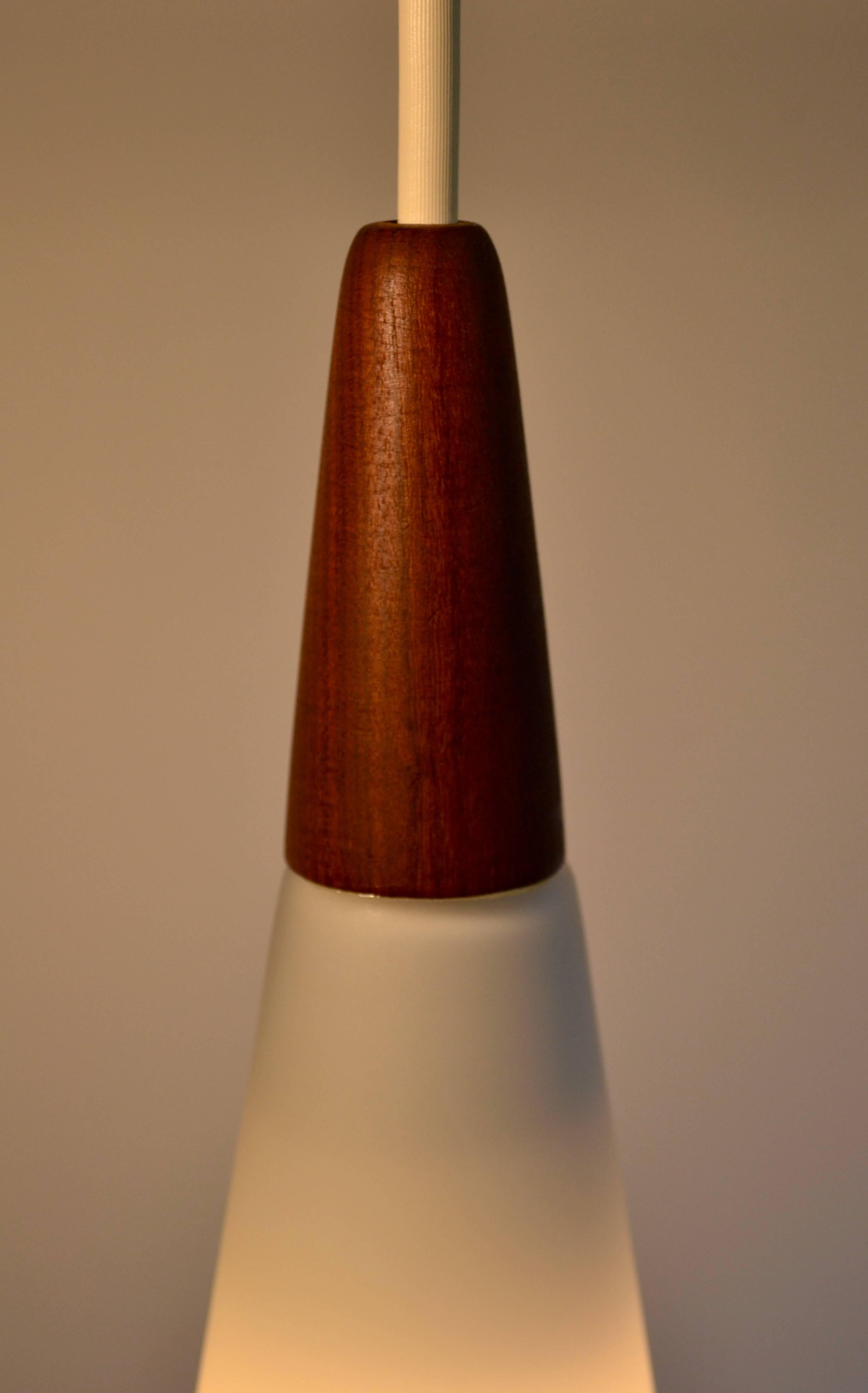 Mid-Century Modern white satin glass and teak cone shaped pendant lights made in Finland by Holmegaard, circa 1960. Nice large size. Excellent condition. Set of three. All original.