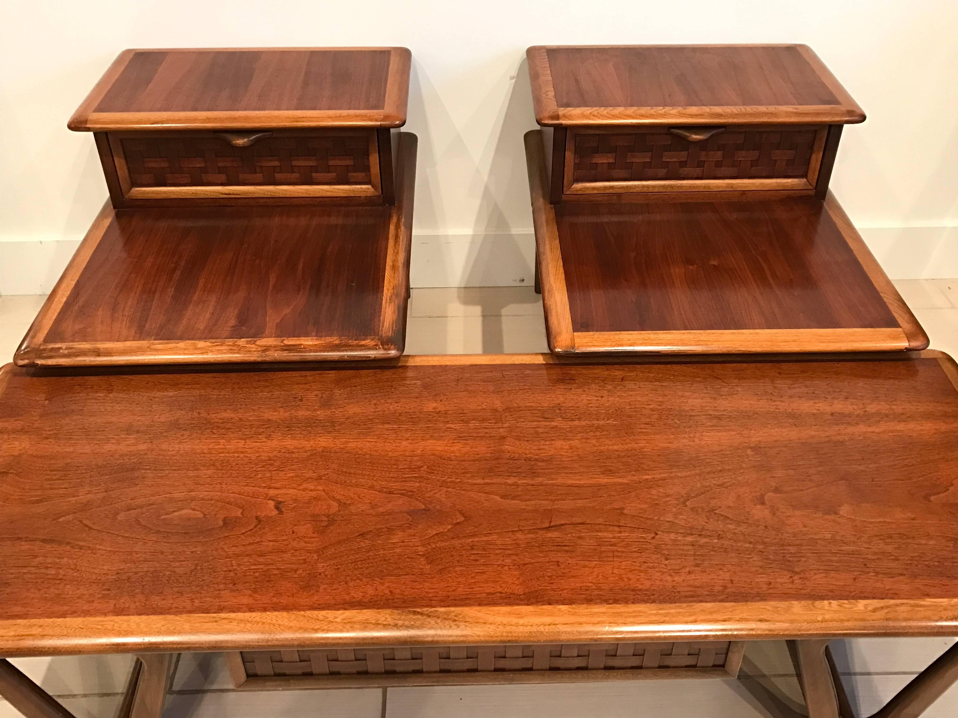Awesome matching set. Pair of end tables and matching coffee table designed by Andre Bus for Lane. Perception line. Coffee table has a drawer under the center of the table with a basket weave design drawer front. End tables are two tiered with